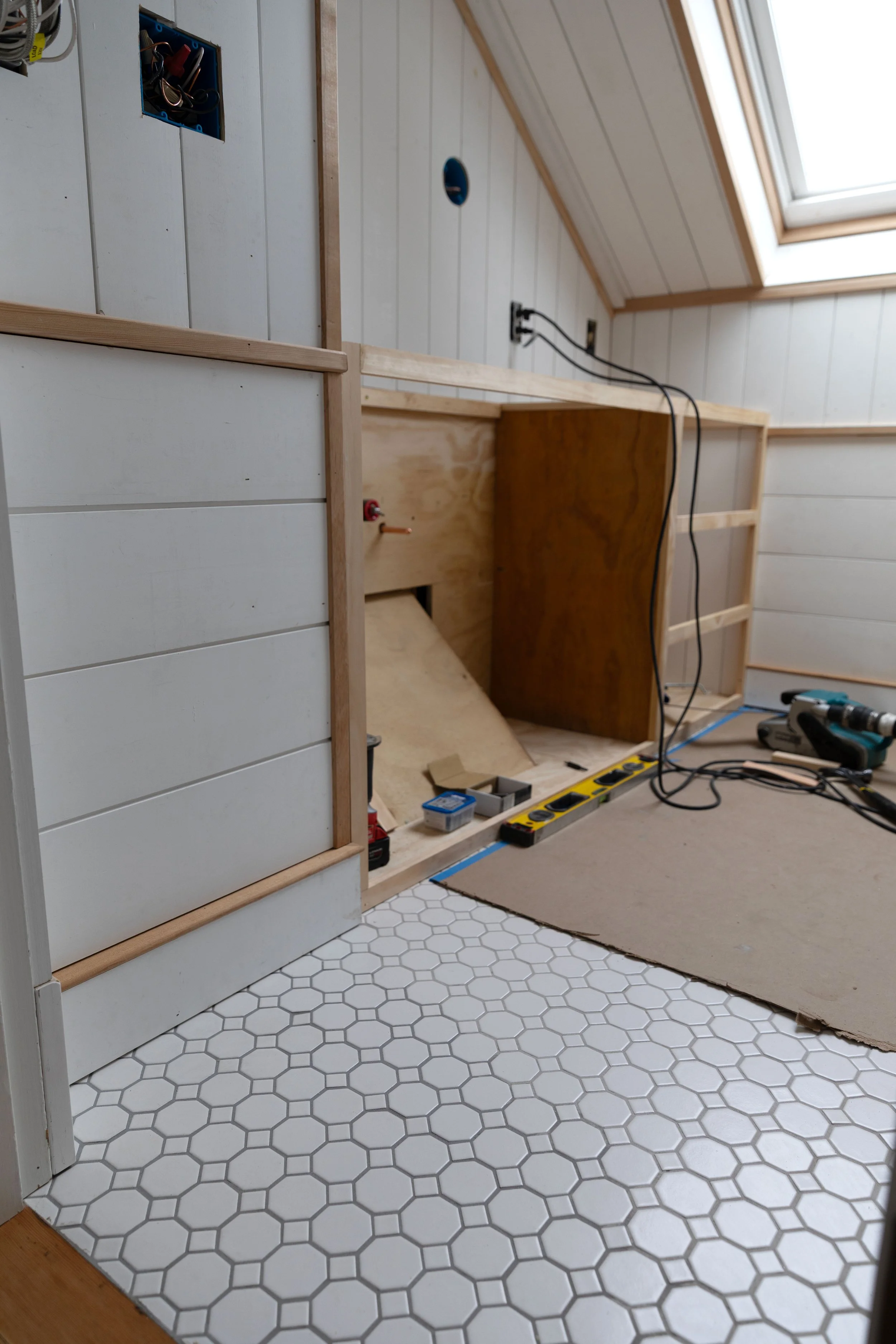 Bathroom view from doorway showing epoxy grout color variation alongside vanity construction in progress