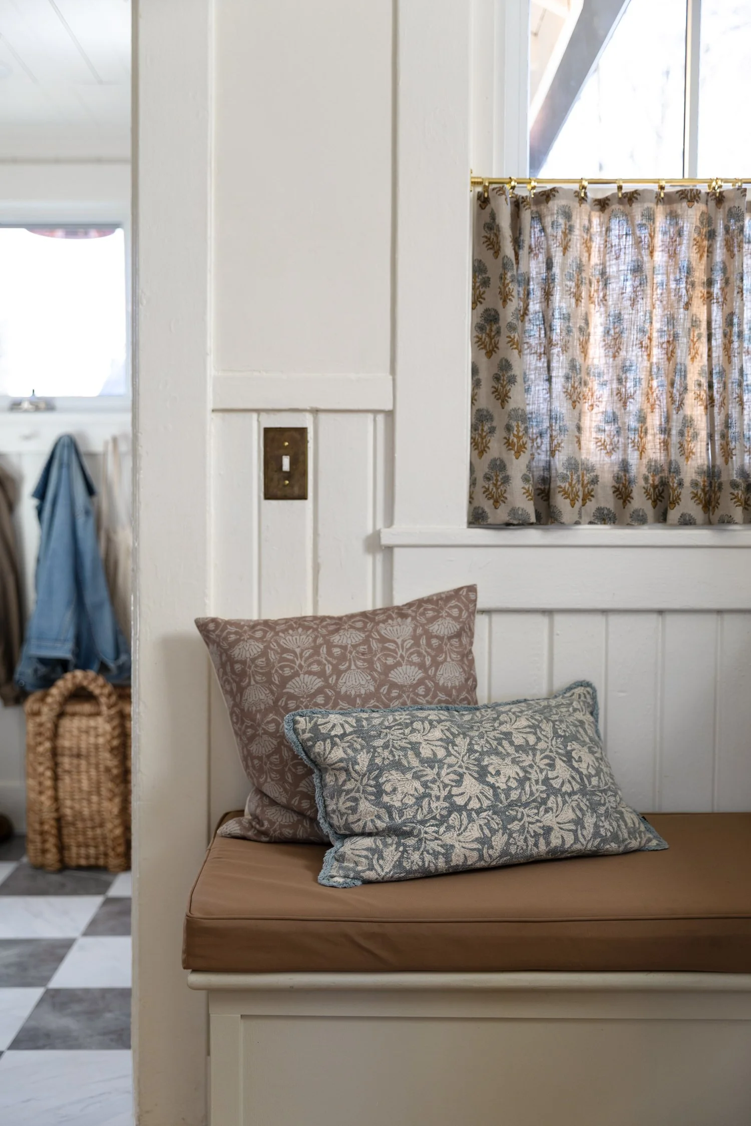 Close-up of pillows and brown performance-fabric bench in cottage kitchen.