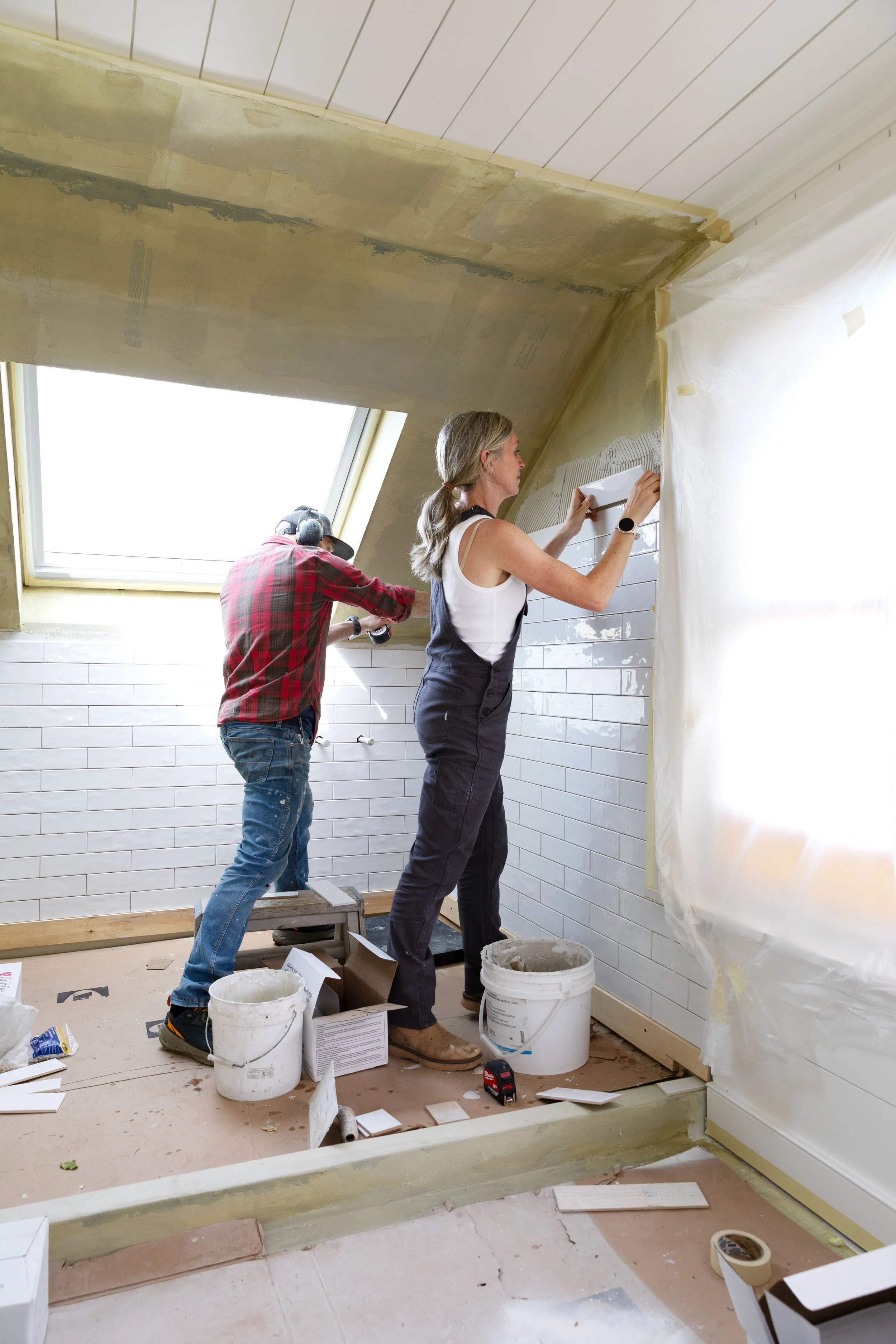 Installing white subway tile in the wet room shower area
