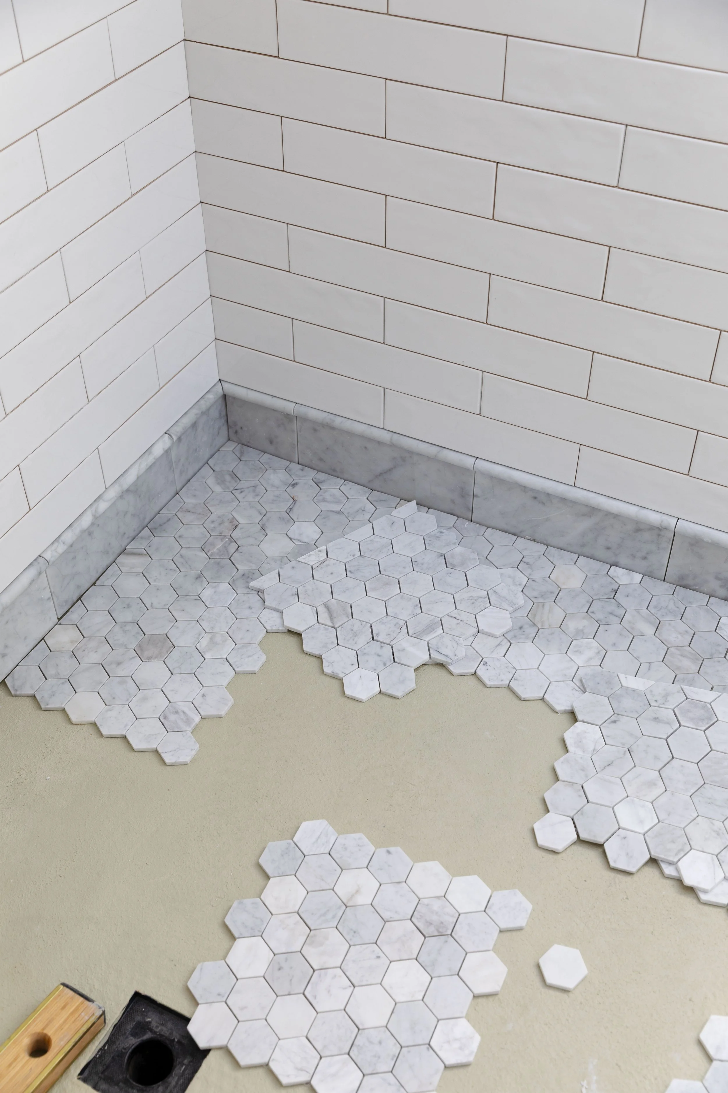 Marble hex tile in the shower with white subways on the walls
