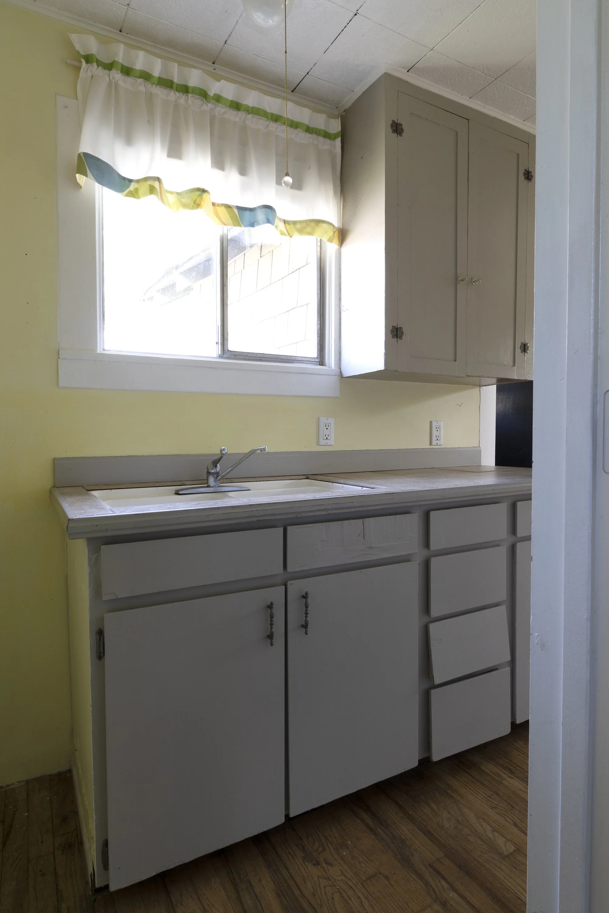 Before photo of the Poplar Cottage kitchen showing mismatched cabinets and outdated finishes.
