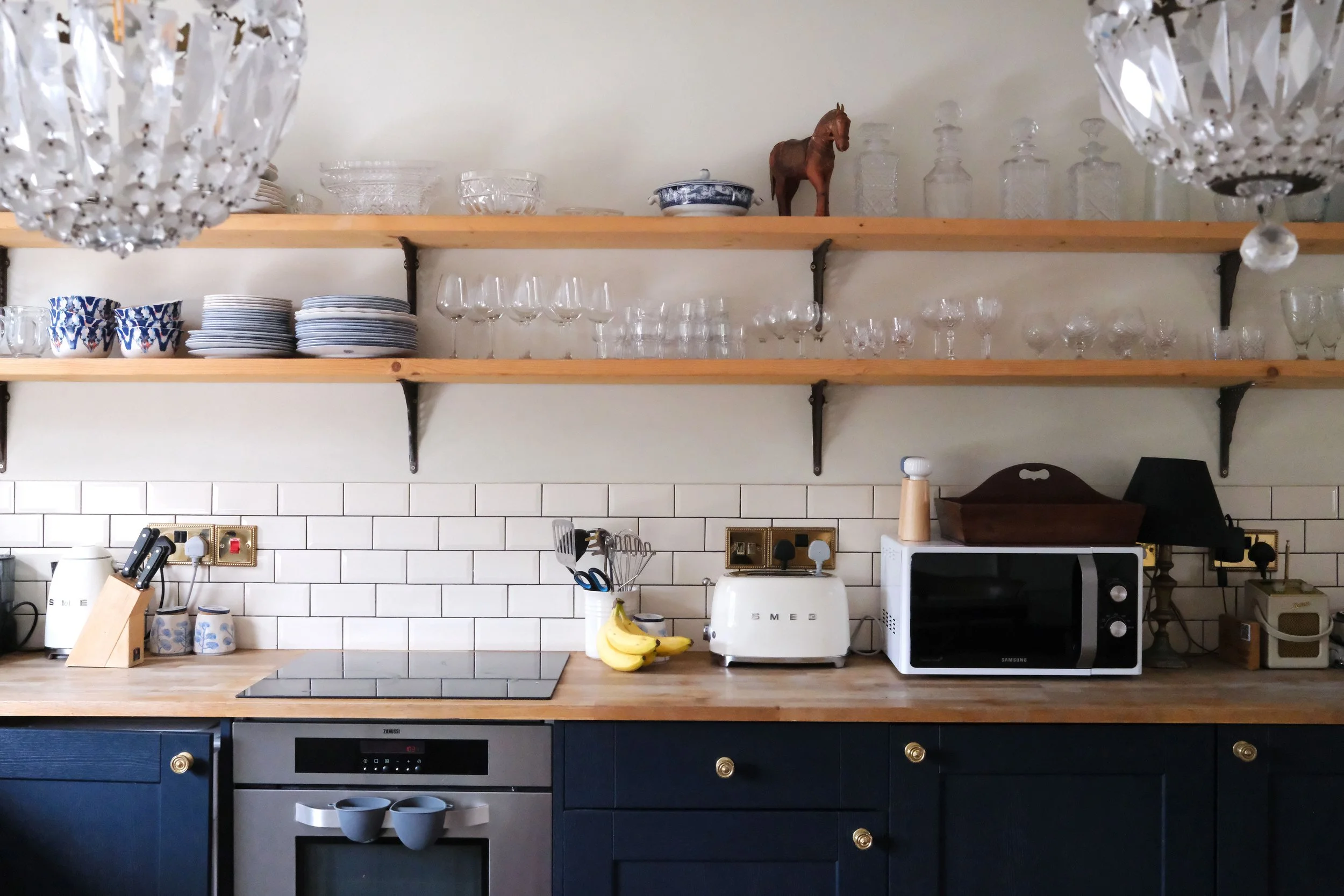 Open wooden kitchen shelves filled with glassware, dishes, and blue-and-white ceramics