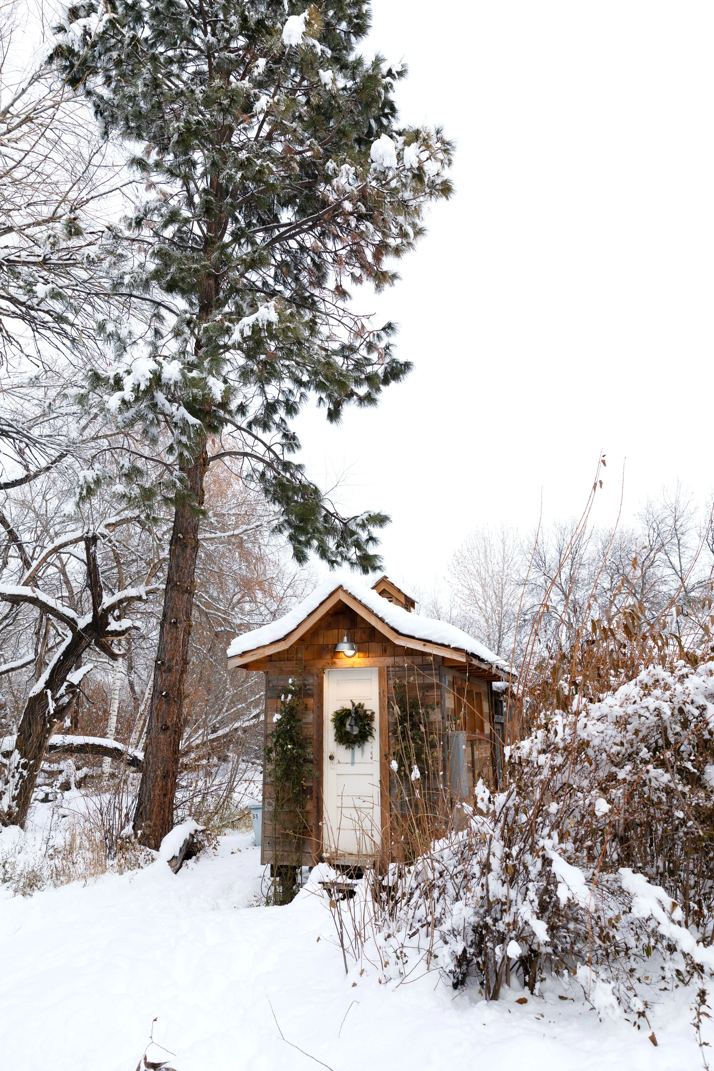 Classic chicken coop with natural evergreen wreath for simple holiday charm.
