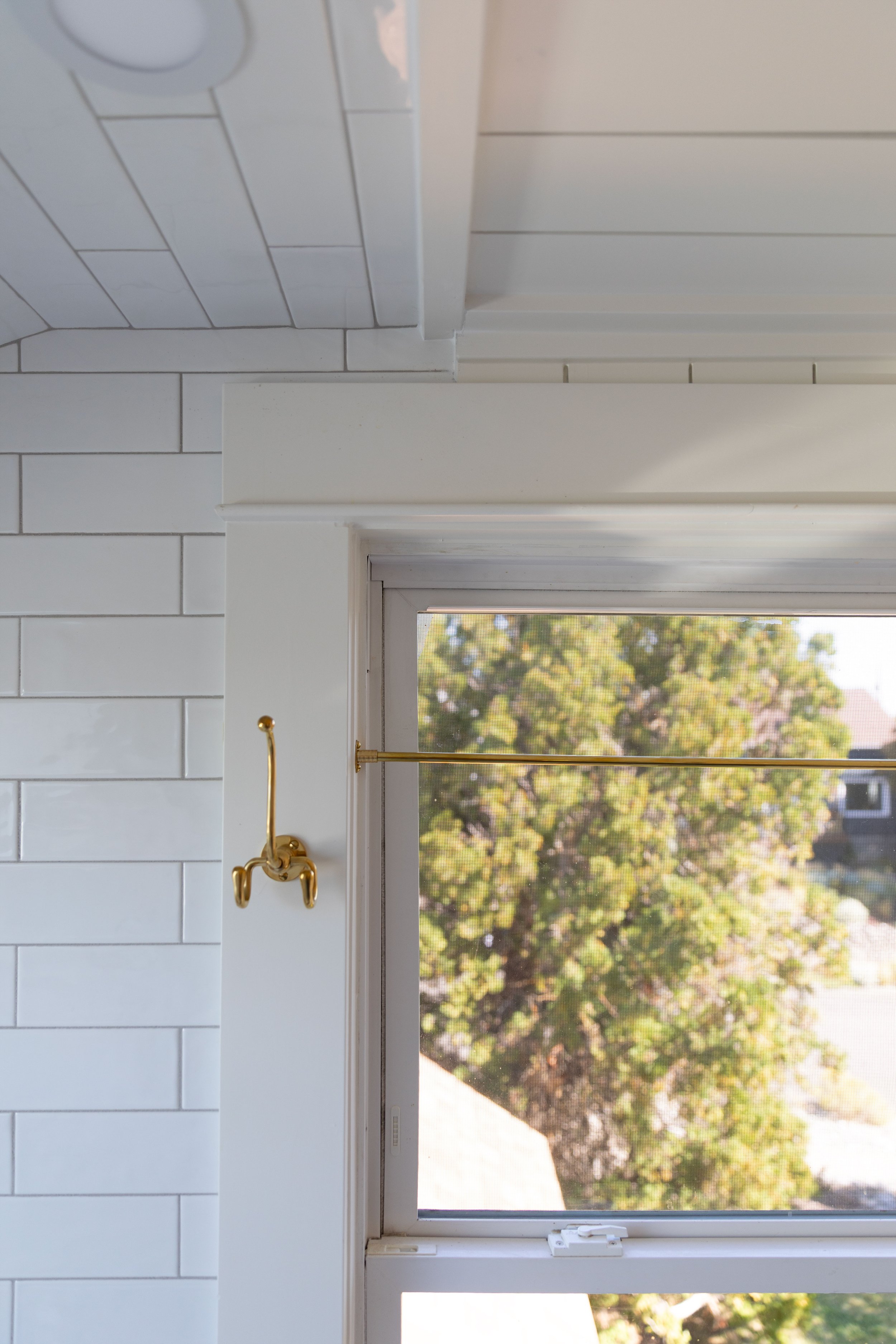 Brass rod and hook mounted at a bathroom window for a short cafe curtain