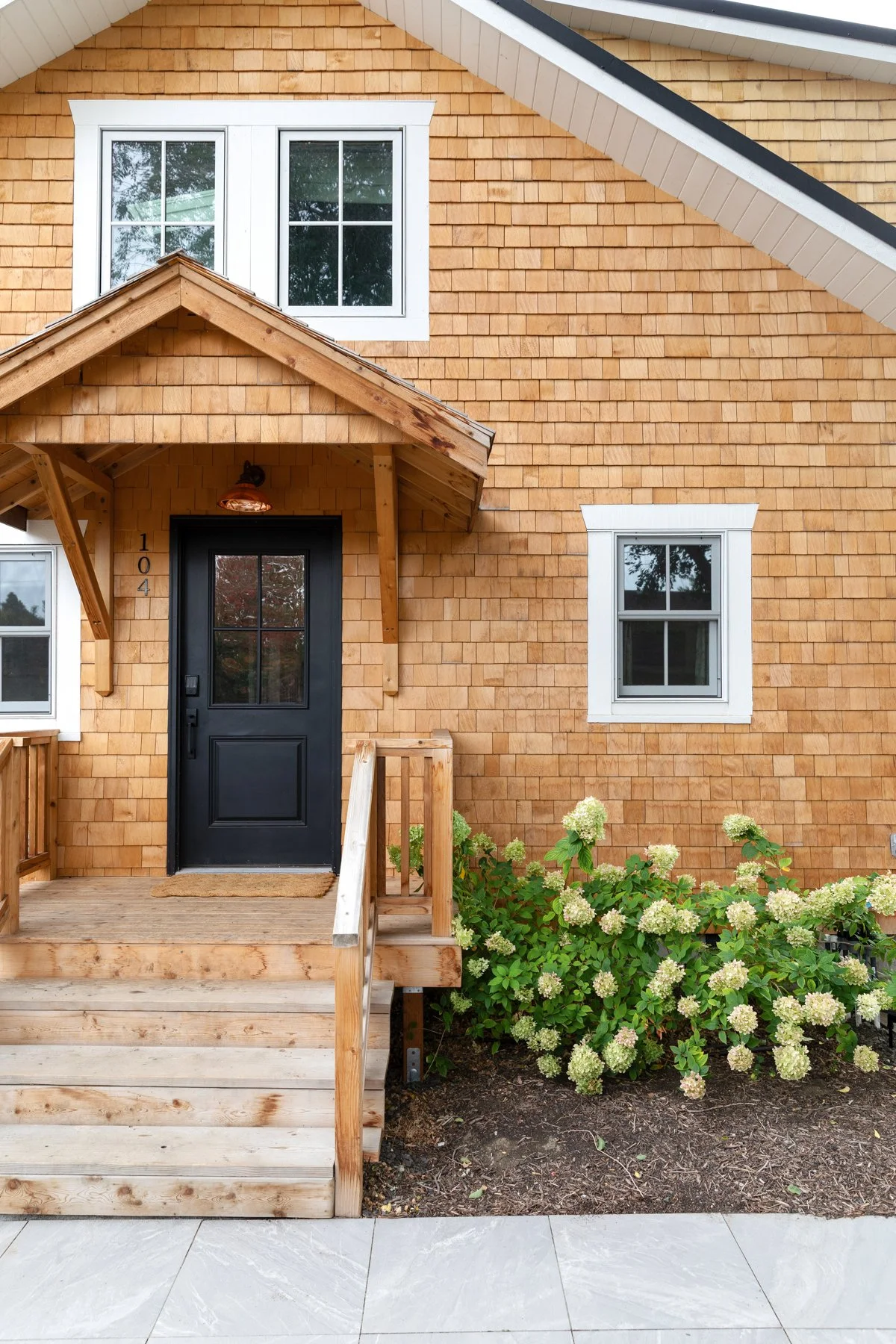 Alaskan yellow cedar siding with limelight hydrangeas, black door, copper light, and white windows