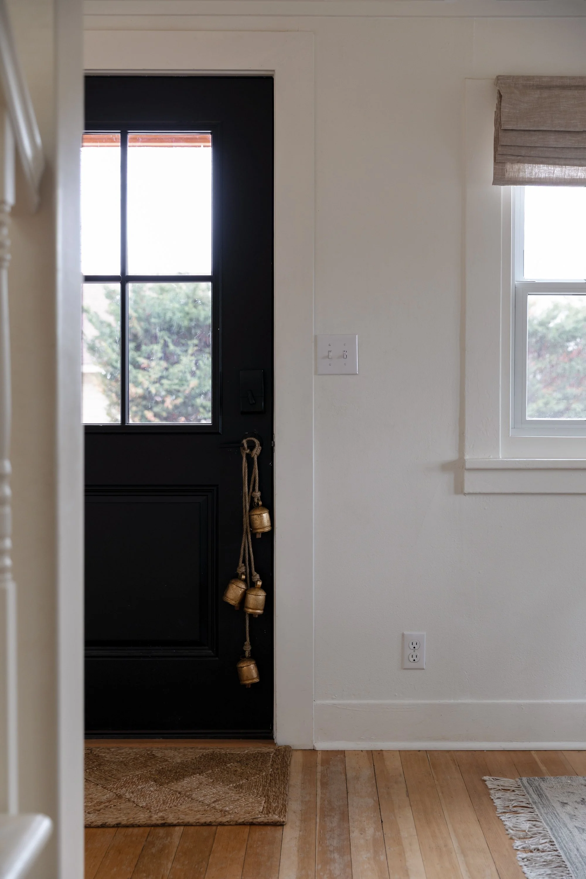 Interior front door decorated with brass bells for Christmas at the Poplar Cottage