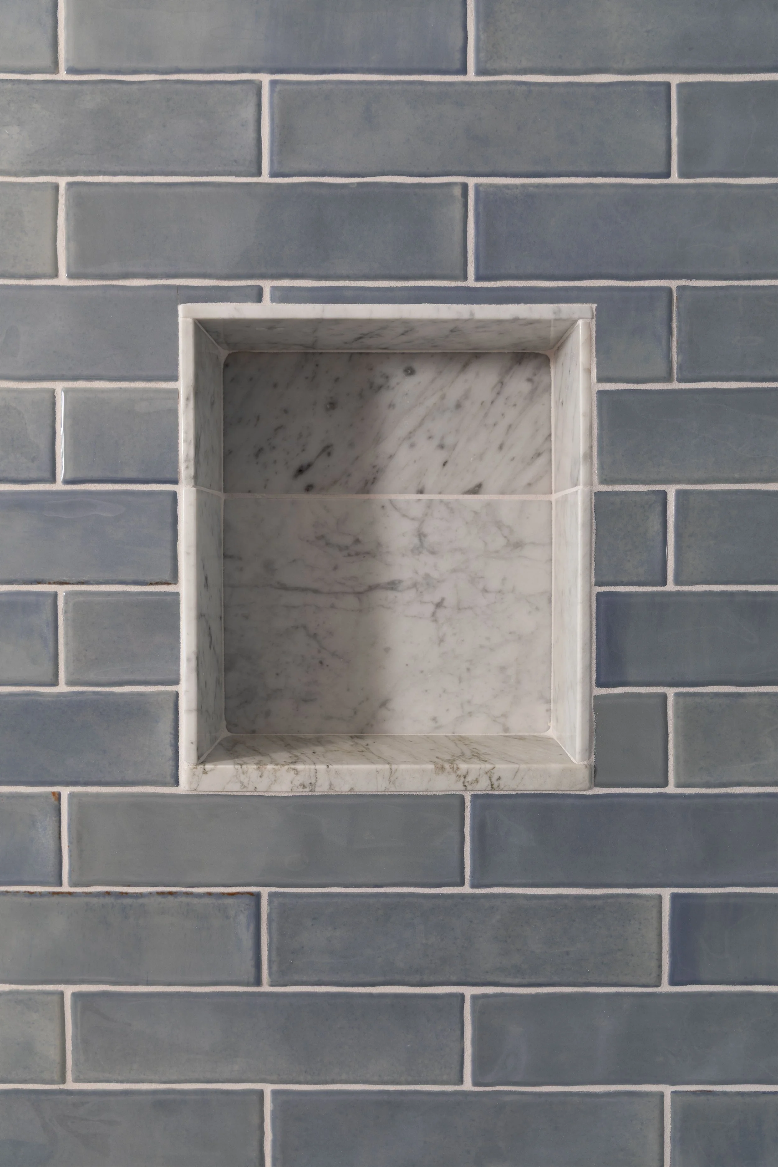 Blue subway tile and marble shower niche with epoxy grout