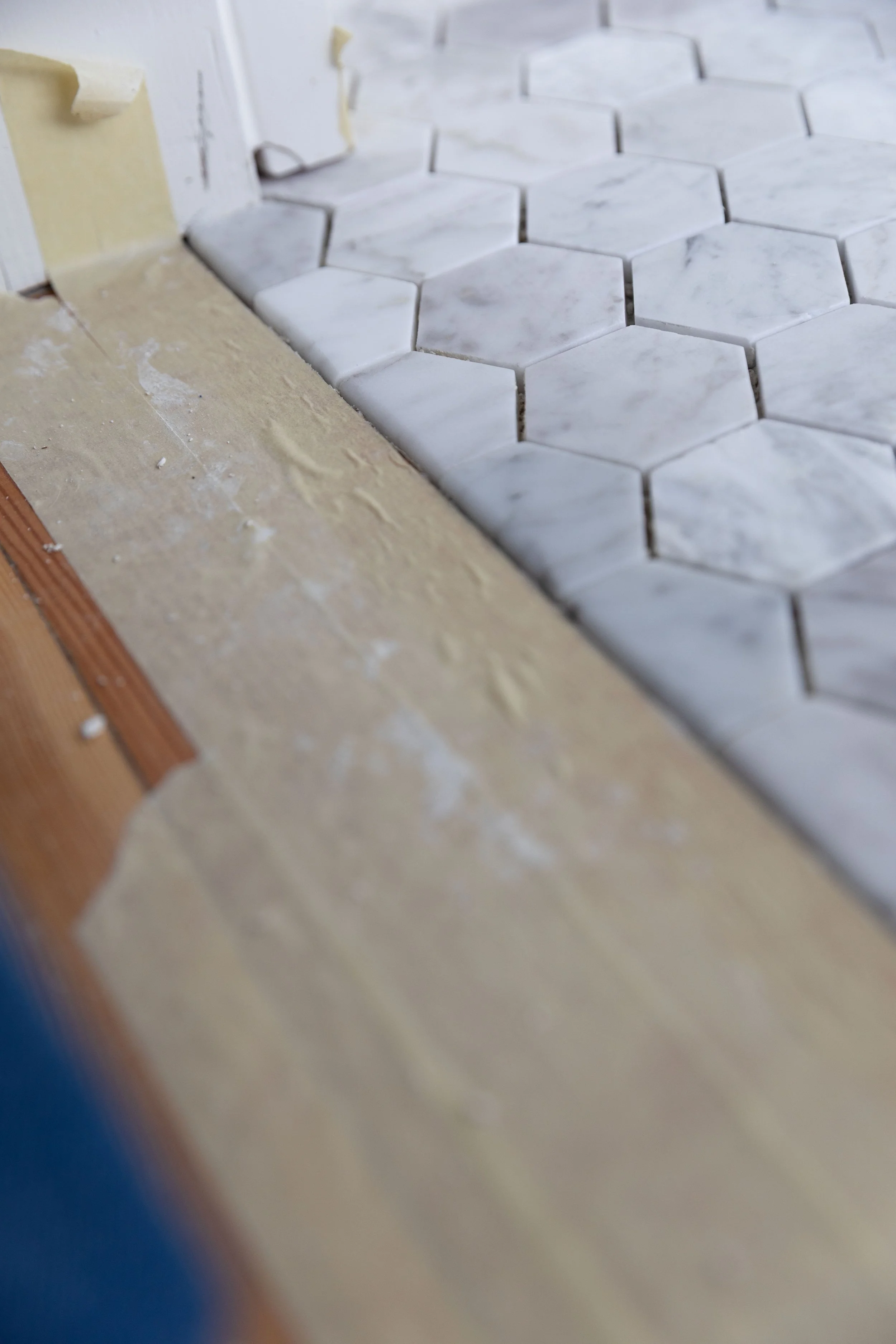 Curved honed marble hex tiles at the doorway to the bathroom for a smooth transition