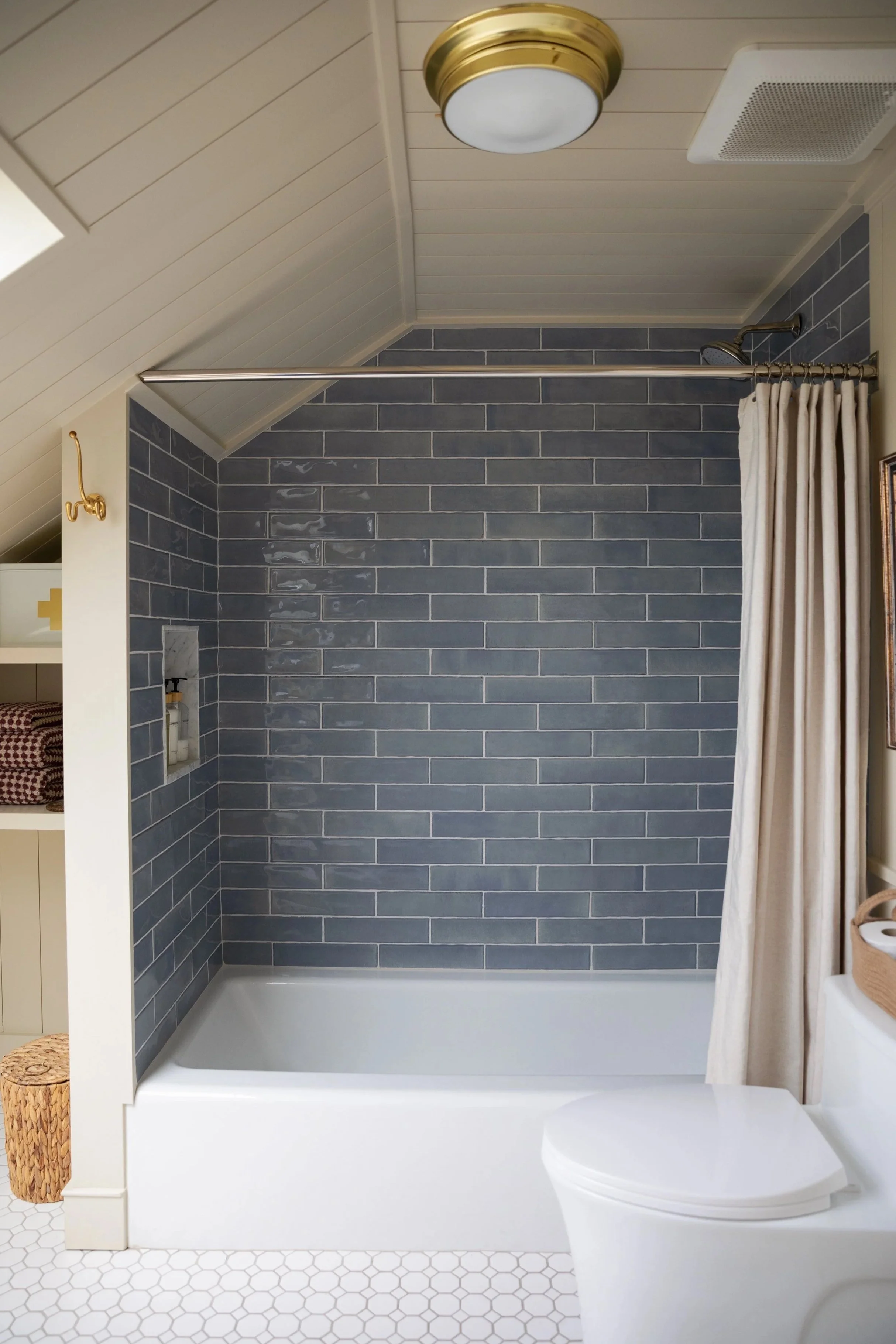 Hanging a shower curtain rod in an attic bathroom with sloped ceilings, blue tiles, and low height