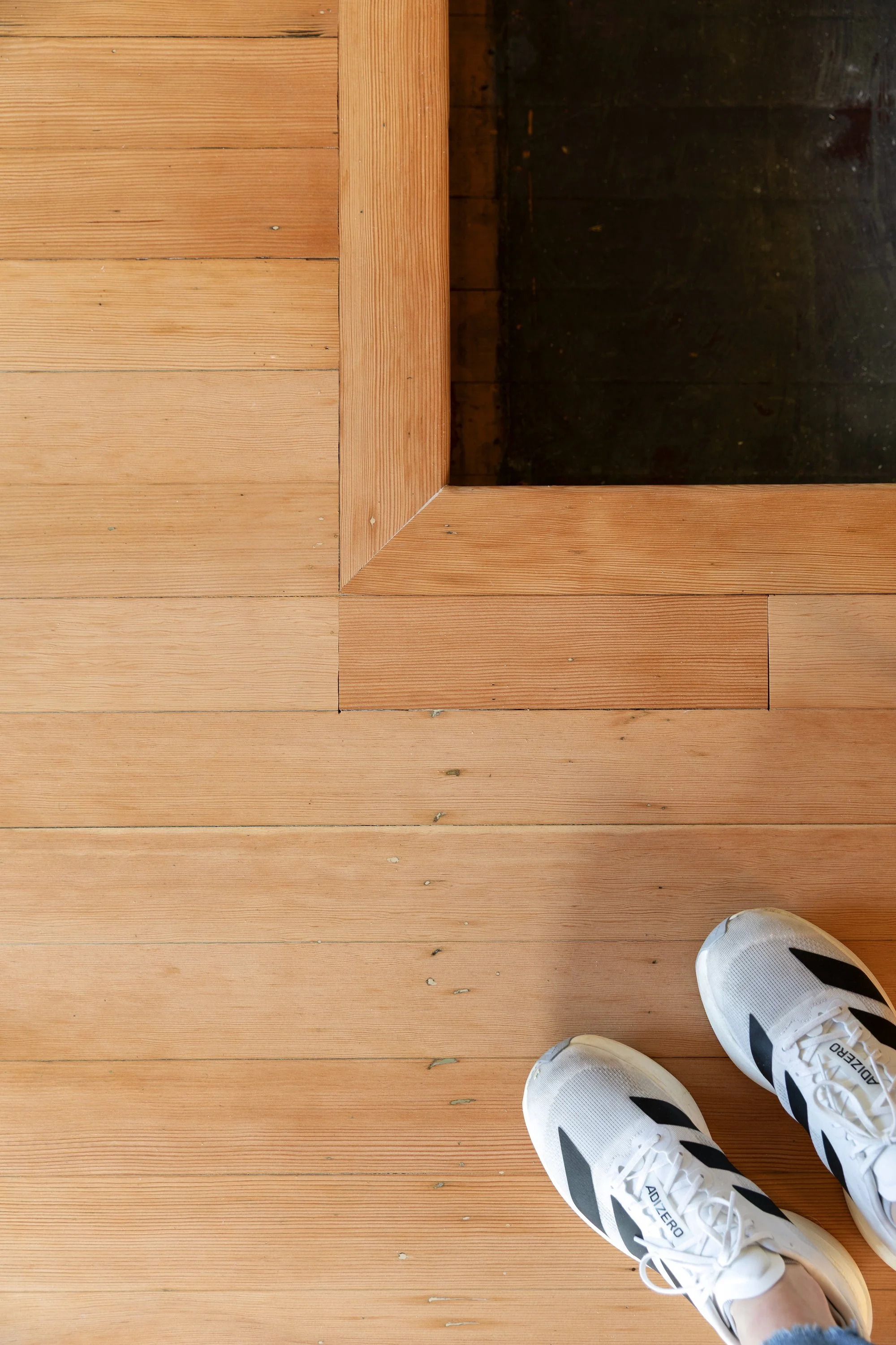 Patched areas and carpet damage visible in refinished fir floors, showing old house character