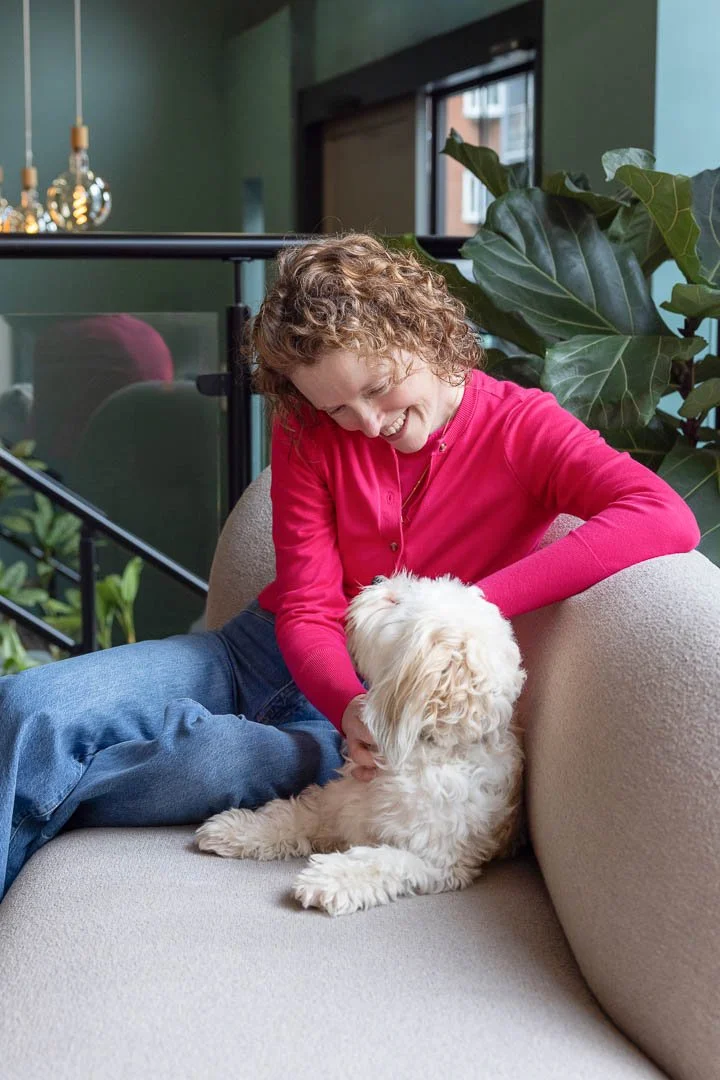 Rachel Goth, sleep coach sitting in a relaxed environment looking at her little white dog, Dotty