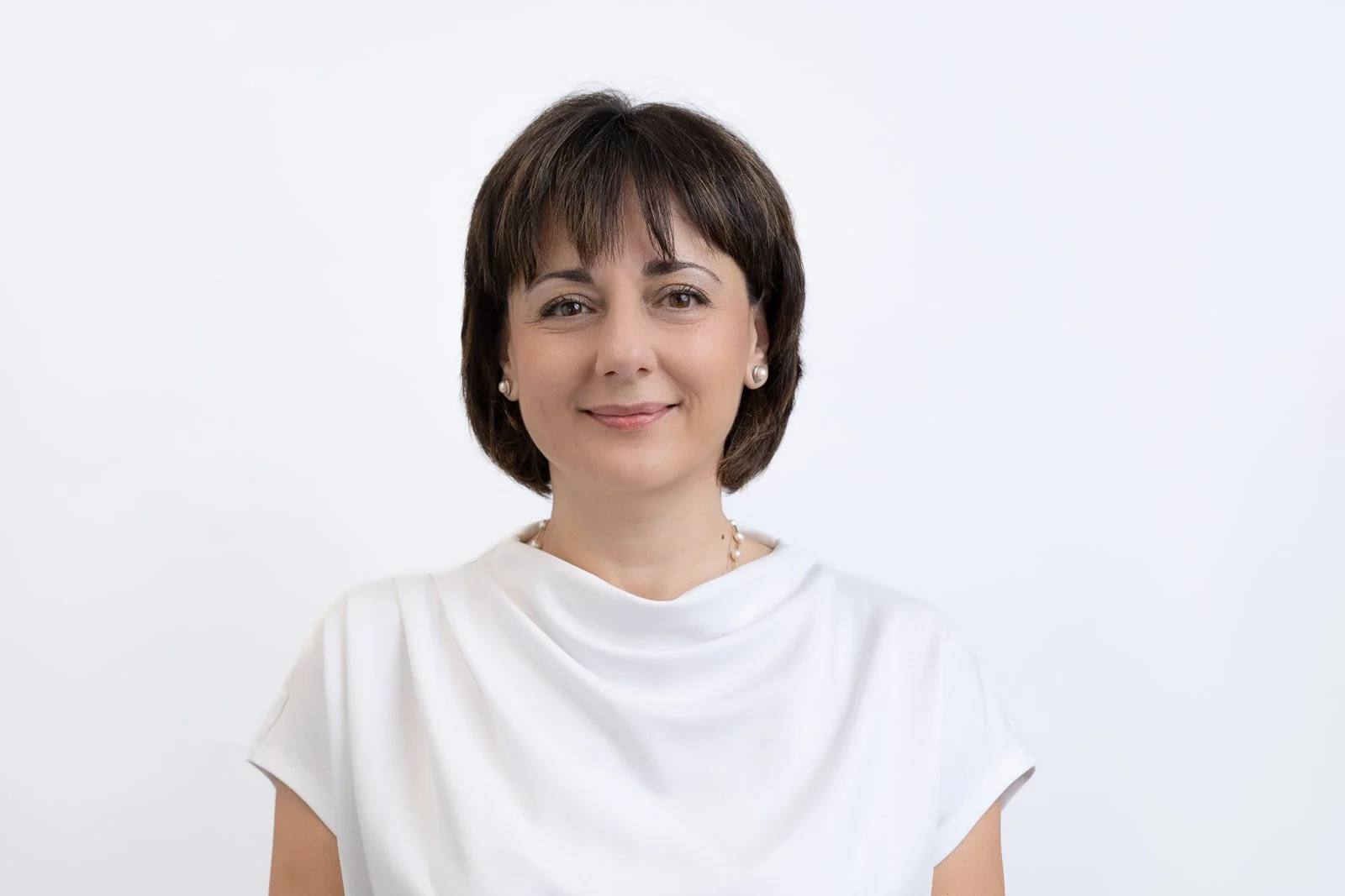 Corporate team headshots photographed with white backdrop on location in London office lady with white top and dark short hair