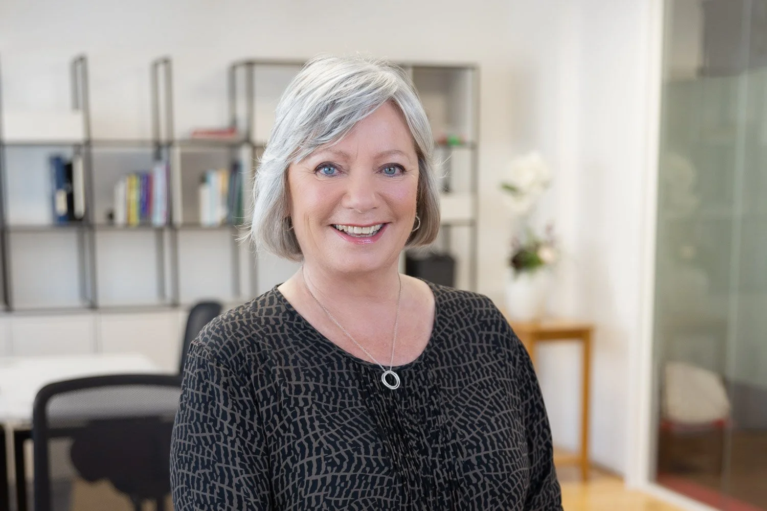 Natural Corporate team headshots on location with female employee smiling confidently at camera and office shown in background 