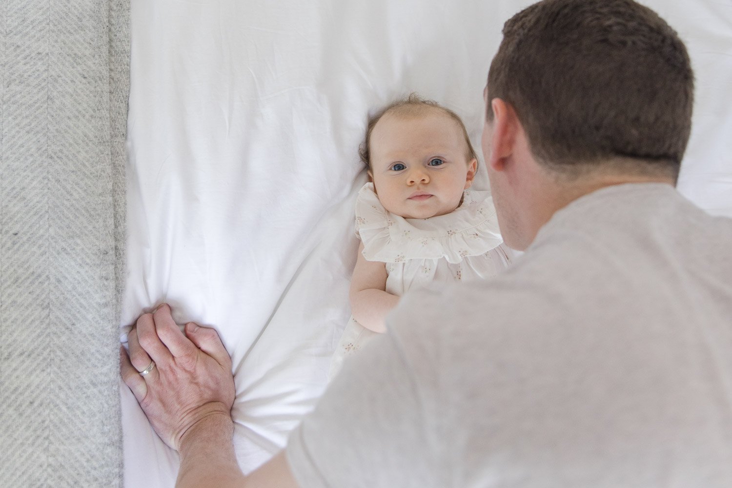 newborn photography London capturing a father looking at his baby whilst the baby is looking to the camera.d