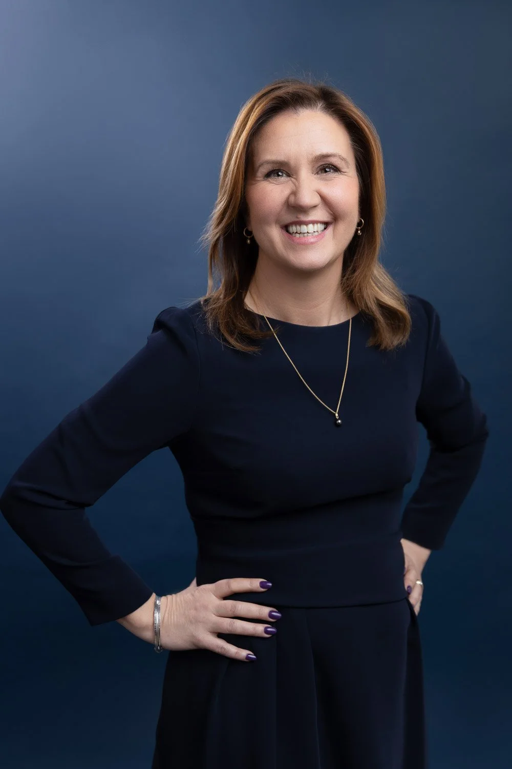 Corporate headshot photographer London natural portrait of business owner against blue backdrop