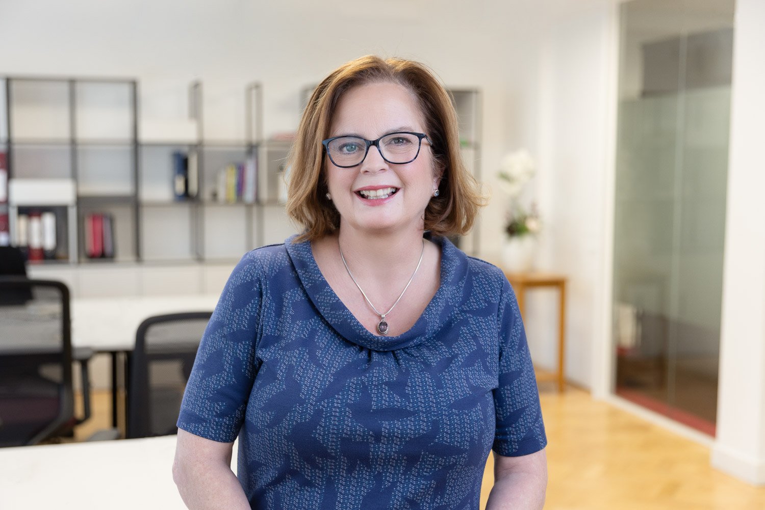 Corporate team headshots photographed on location in London office with female wearing a blue outfit smiling naturally at the camera