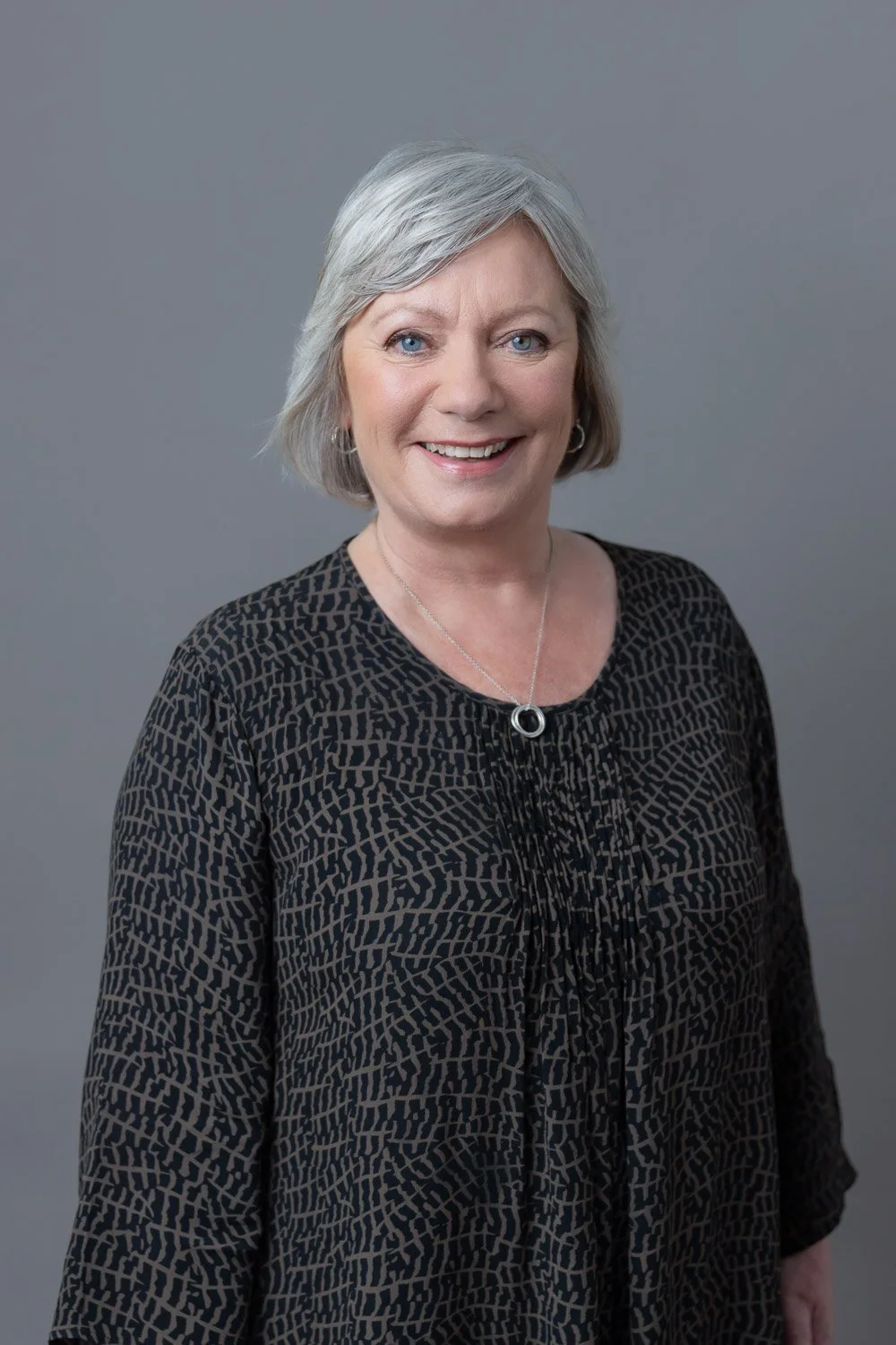 Corporate headshot session for company team in London with female employee with a dark top against a grey backdrop