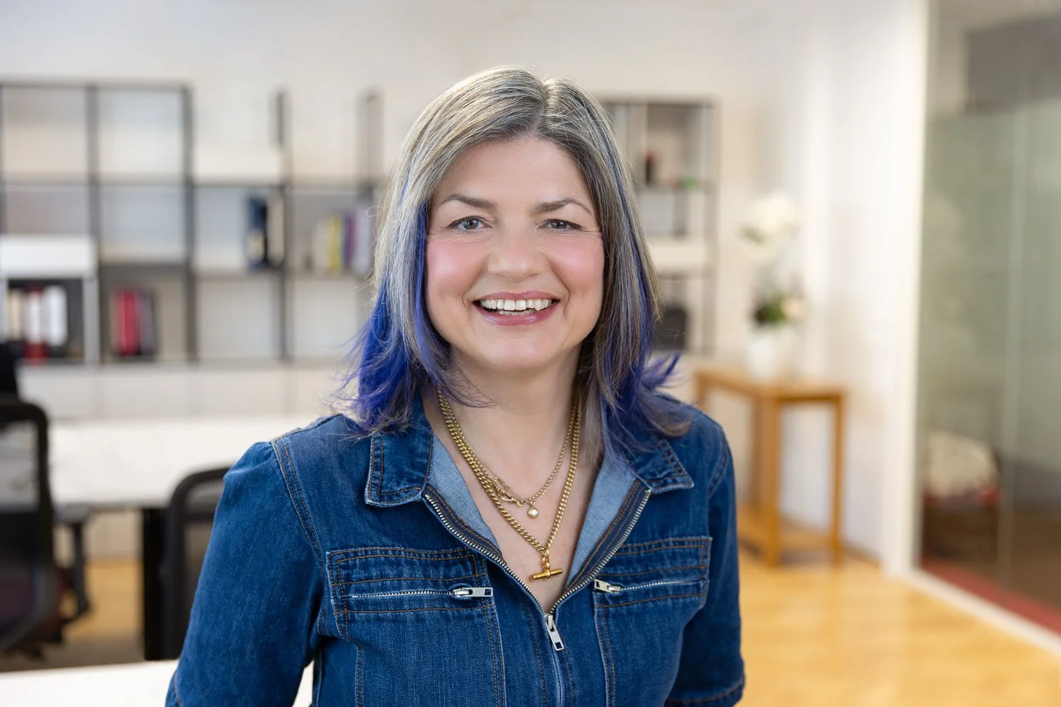 Relaxed Corporate team headshot photograph with female team member smiling at camera wearing a blue denim outfit 