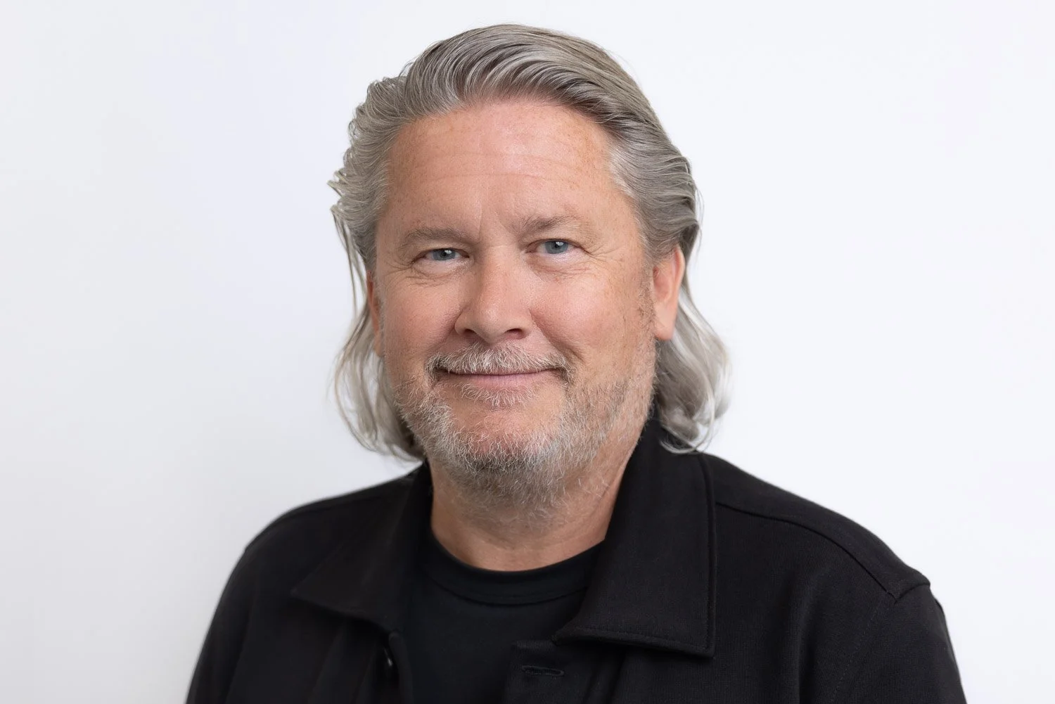 Corporate headshot of a man smiling to camera with a white backdrop