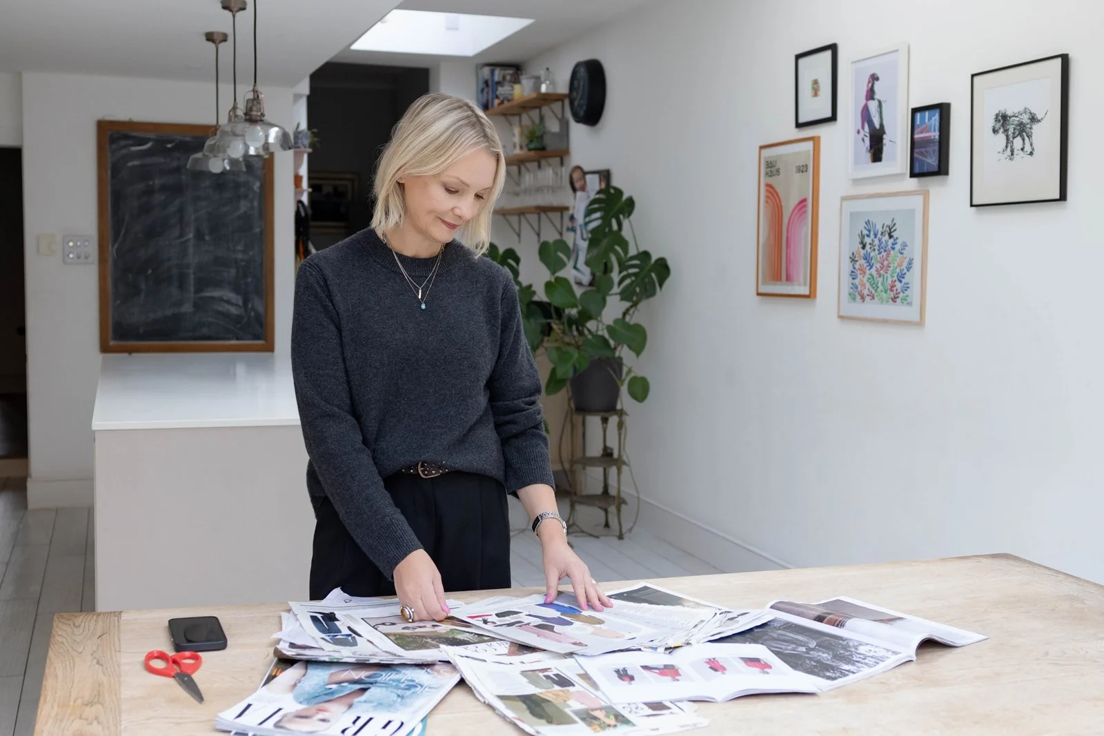Personal branding photography showing a stylist in her kitchen looking at magazines spread out on the kitchen table.