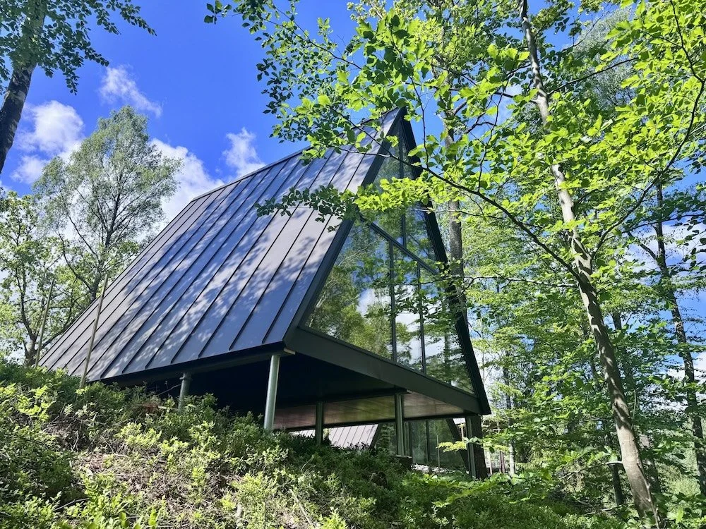 Modernt hus med stora glasfönster i en skogsmiljö