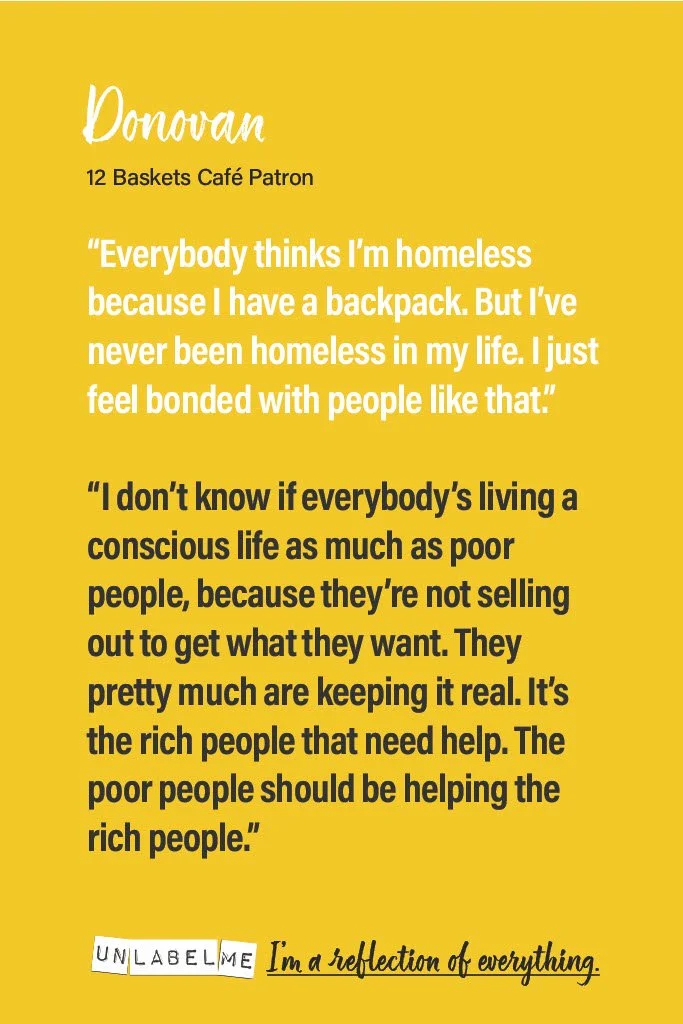 Yellow poster with black and white text quoting a person named Donovan, identified as 12 Baskets Café Patron, discussing homelessness and empathy, and including the phrase 'I'm a reflection of everything.'