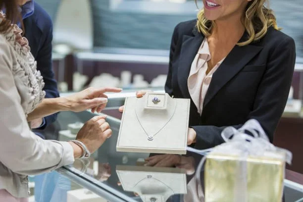 Customer and jeweler examining diamond necklace display in store