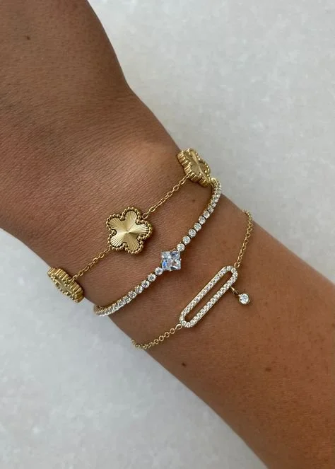 Wrist adorned with gold and diamond bracelets on a light surface.