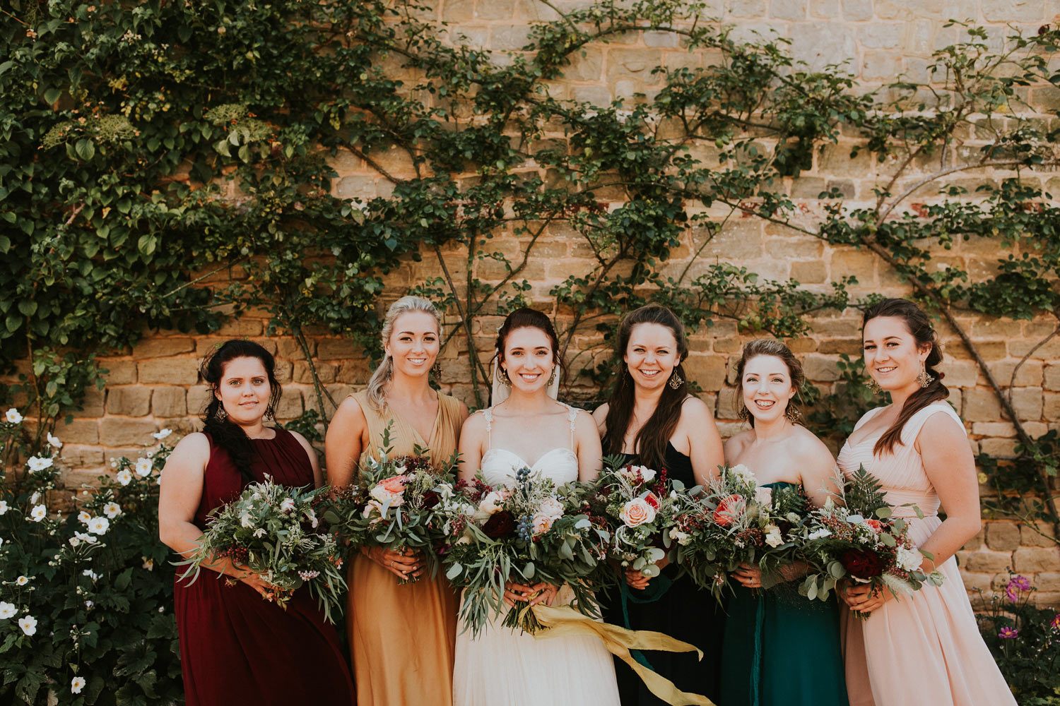 Bride and bridesmaids with rustic woodland bouquets in walled garden