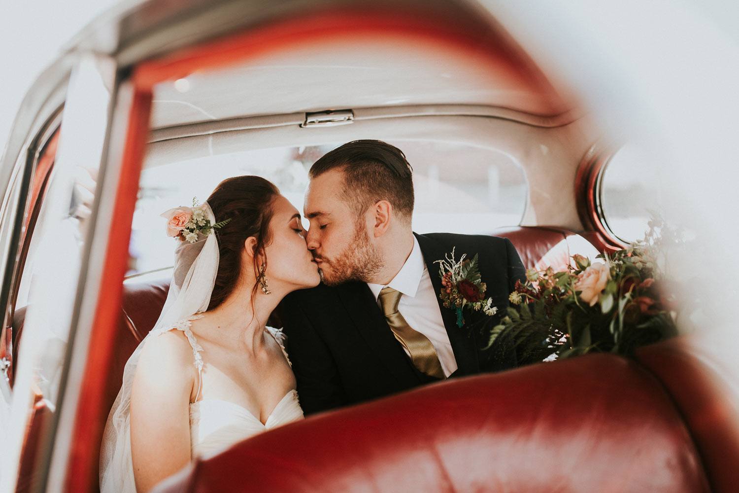 Couple kissing in wedding car with flowers