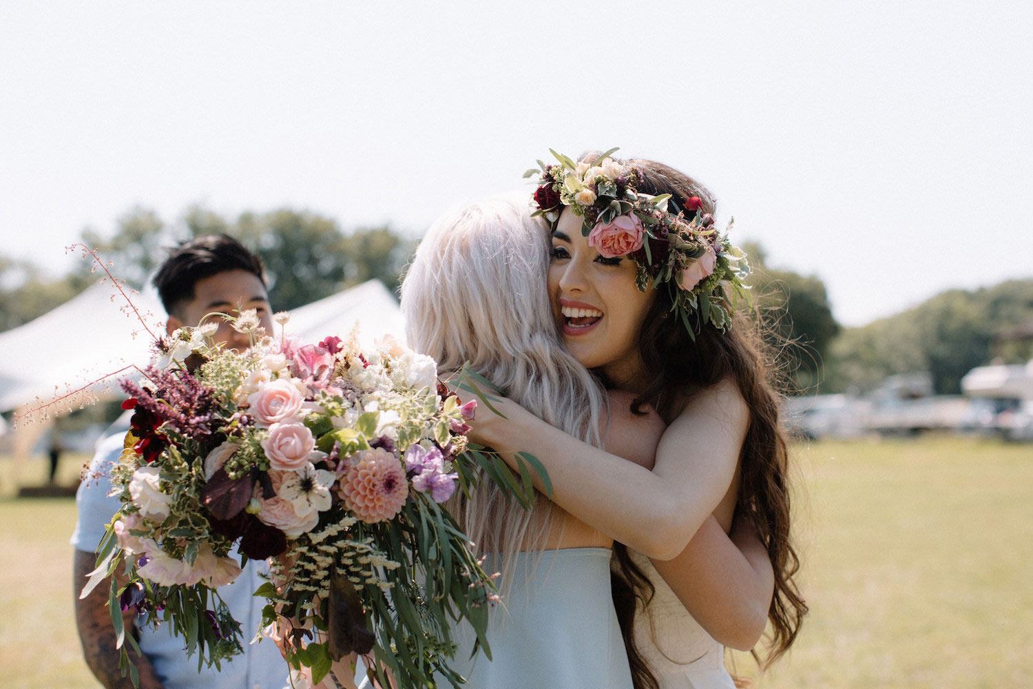 Bride greeting friends with bouquet in marquee