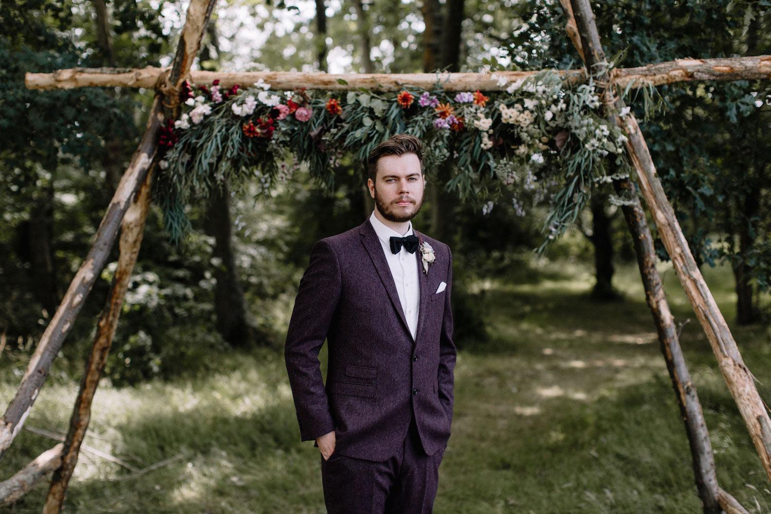 Groom standing under woodland wedding arch