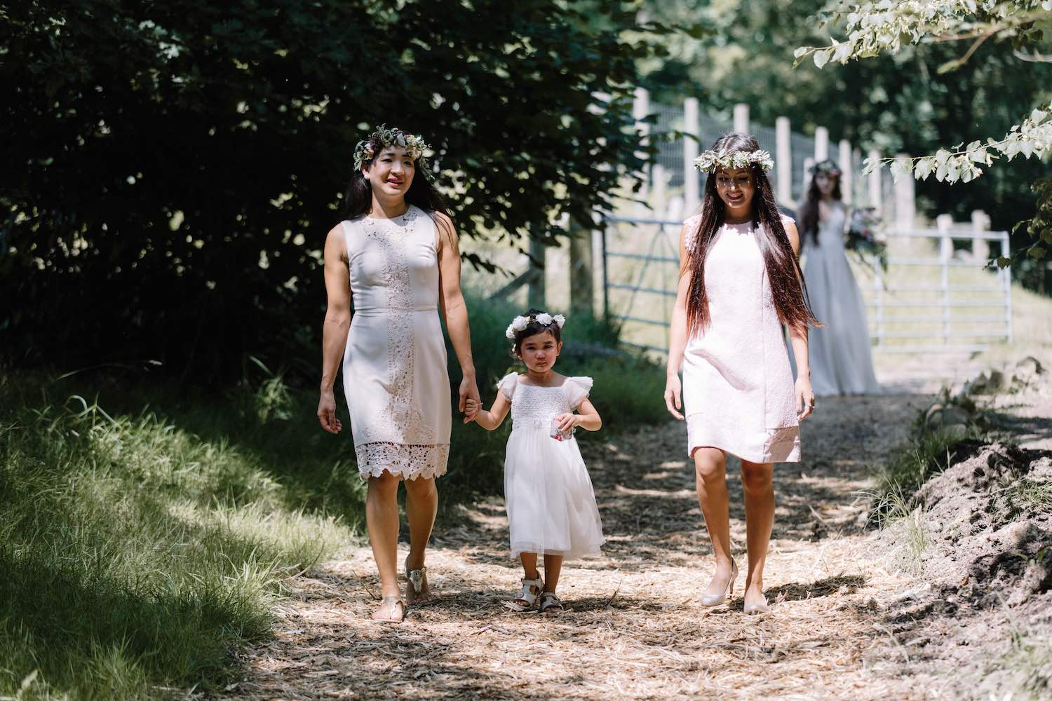 Bridesmaids and flower girl walking to woodland ceremony