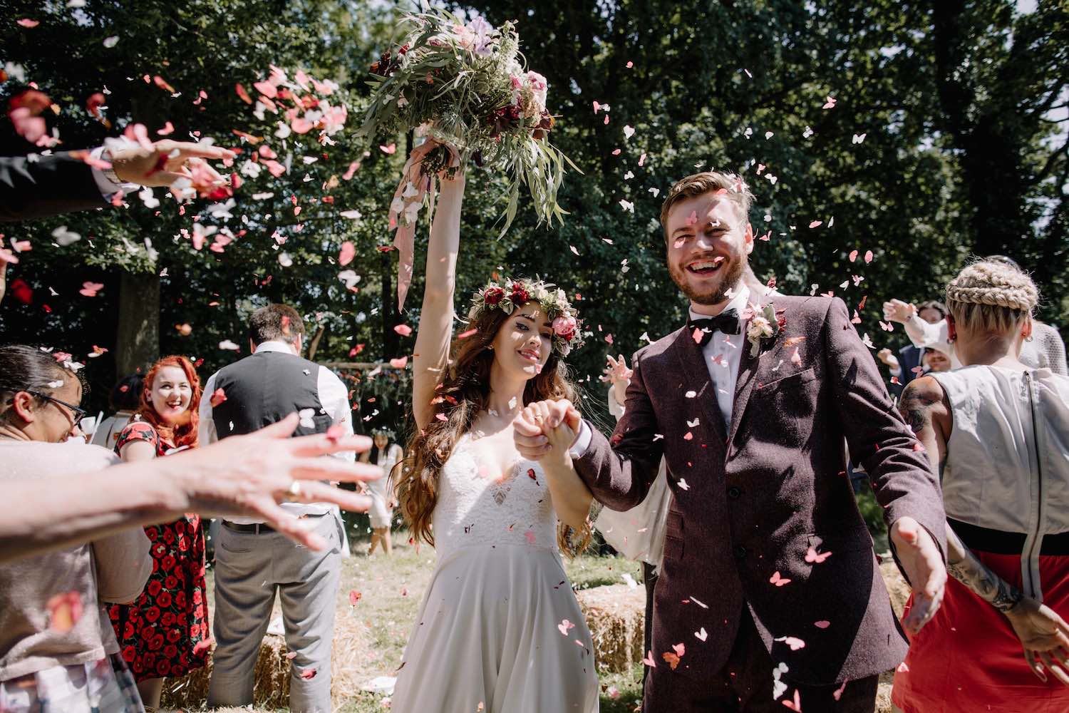 Couple cheering with confetti after woodland ceremony