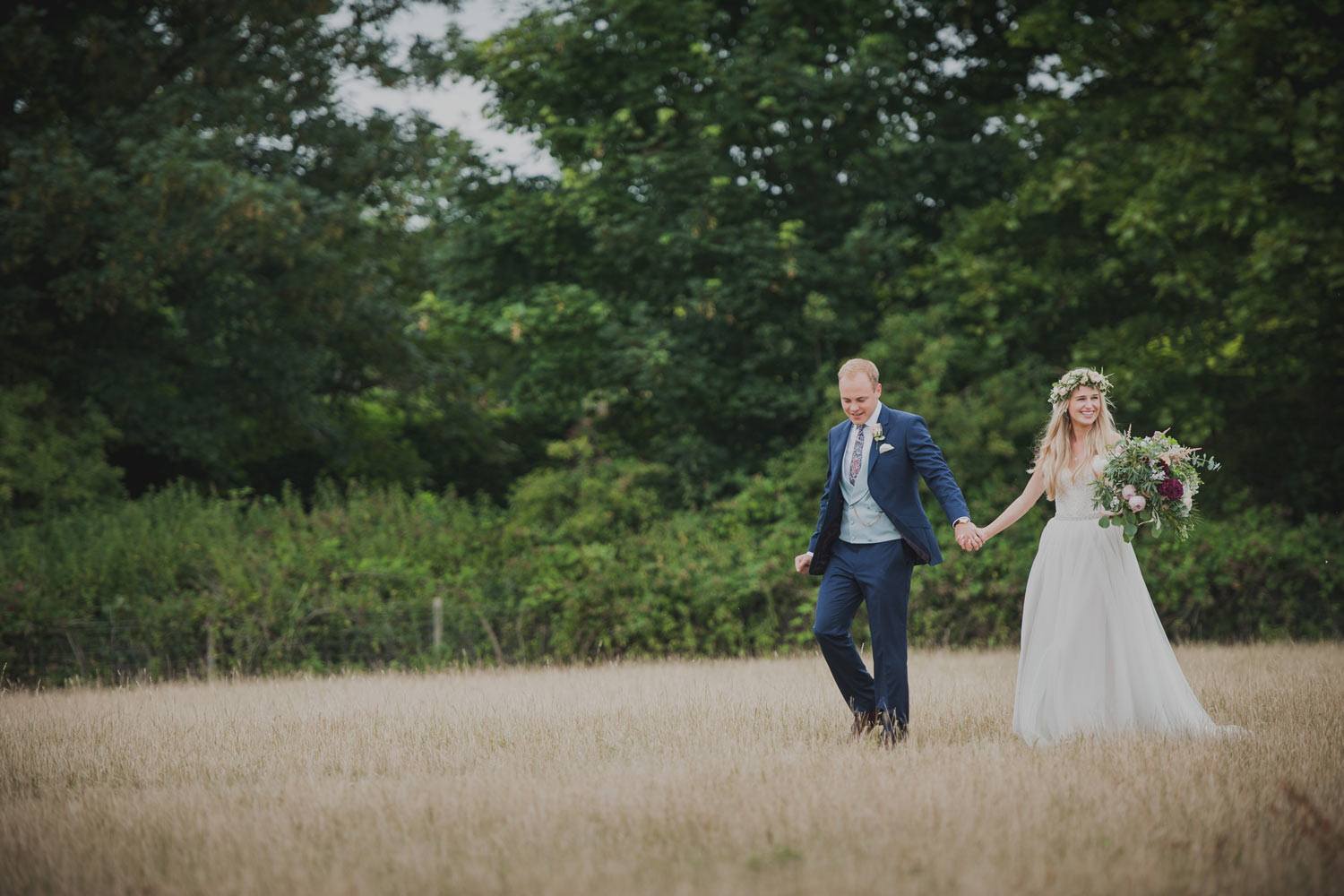 Bride and groom walking in summer meadow