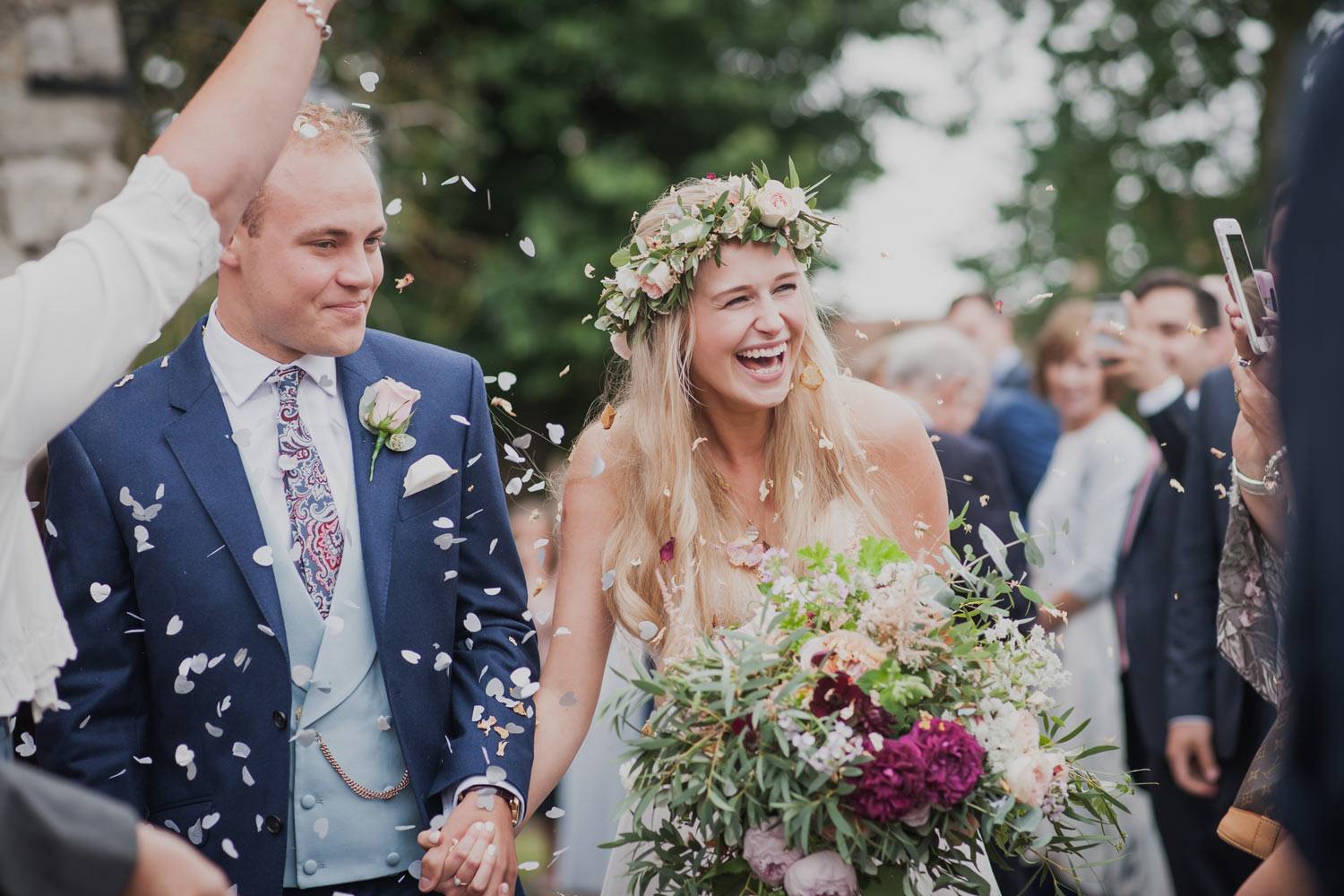 Bride and groom leaving church ceremony with flowers and confetti