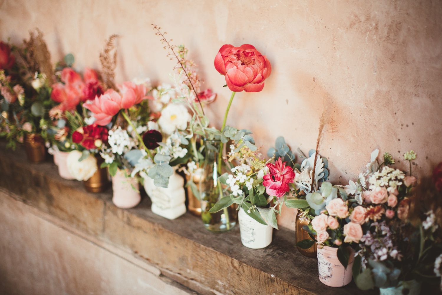 Coral and mint flowers in jars in barn wedding