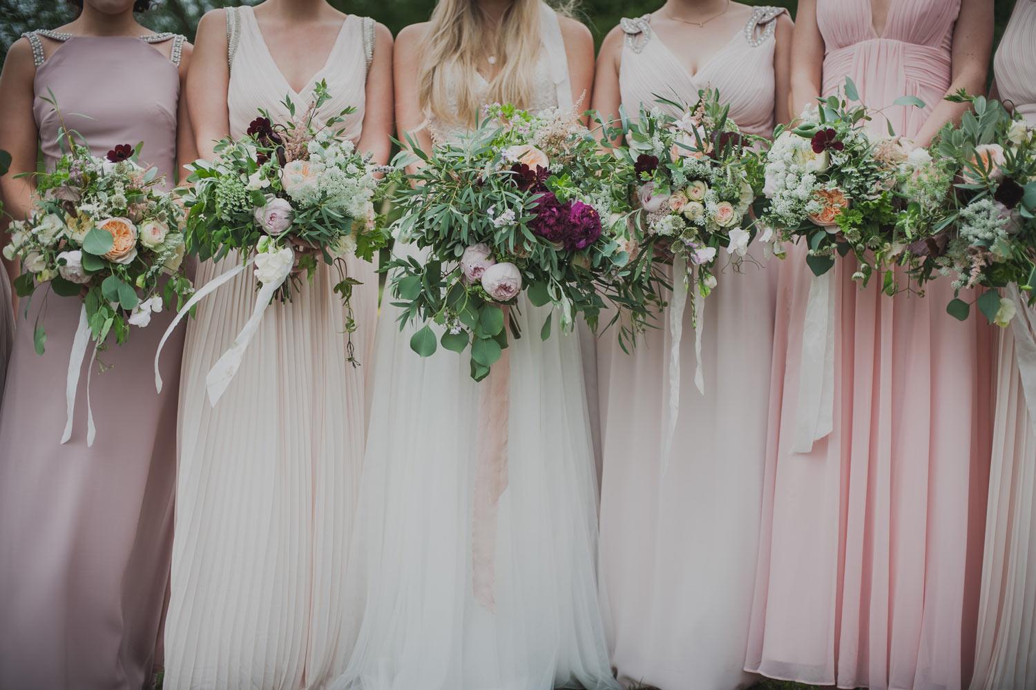 Pale pink bridesmaids holding bouquets in a row