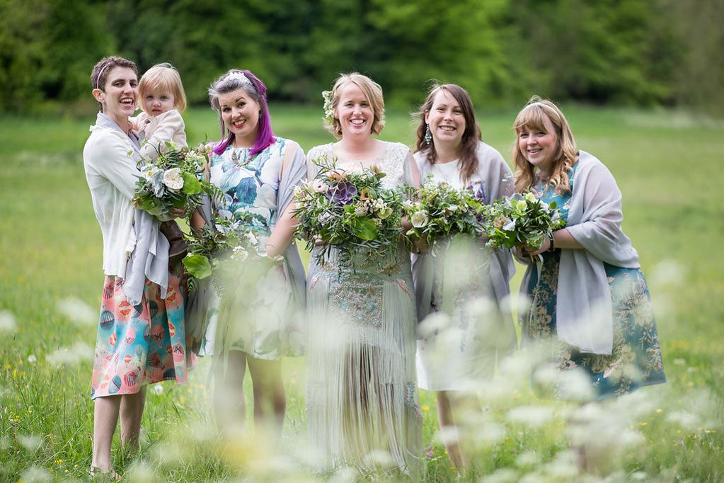 Bride and bridesmaids in spring meadow with wild bouquets