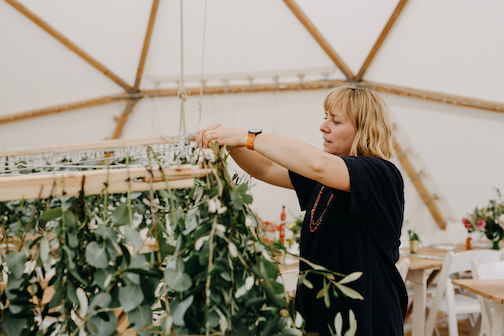 Bea arranging foliage chandelier in wedding marquee