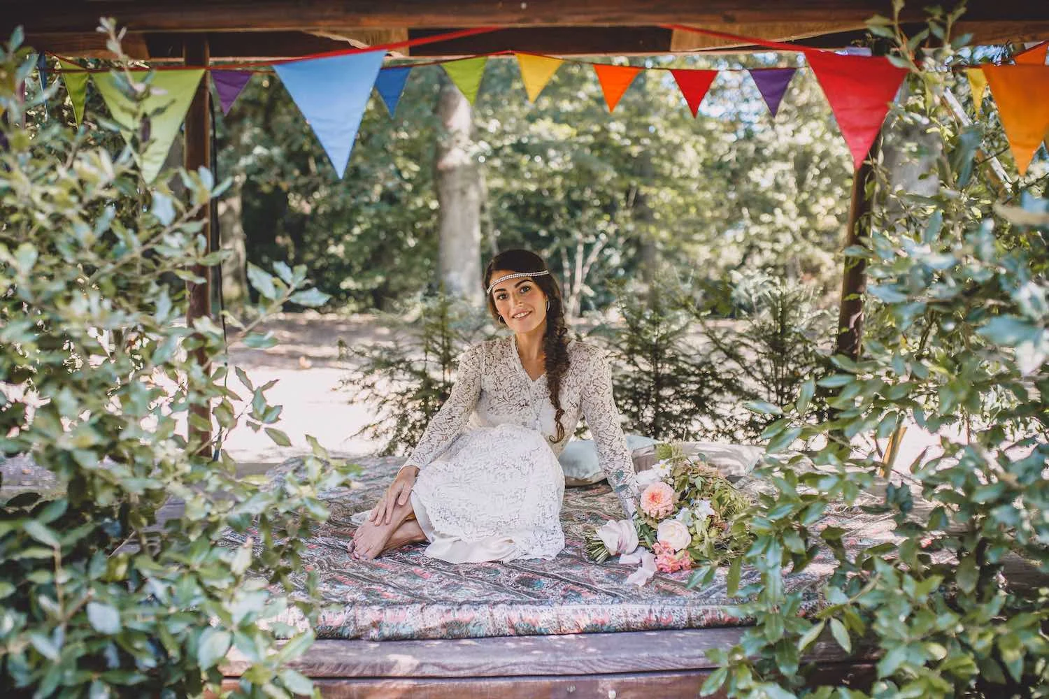 Boho bride on woodland daybed with flowers and bunting