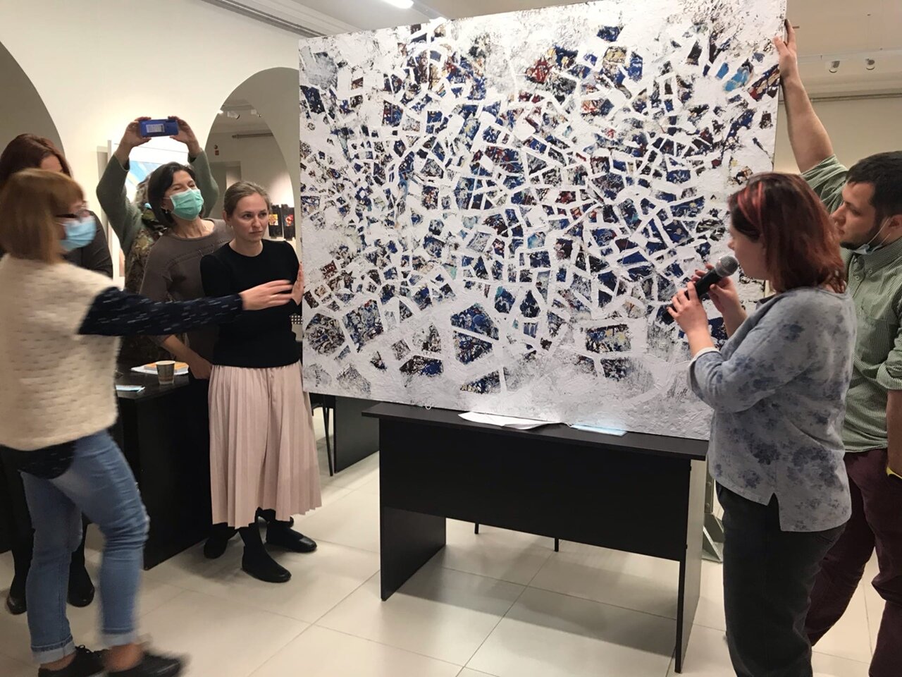  Die Mitarbeiterinnen und Mitarbeiter des Museum diskutieren vor einem abstrakten Gemälde über die Herausforderungen von Bildbeschreibungen abstrakter Kunst. 