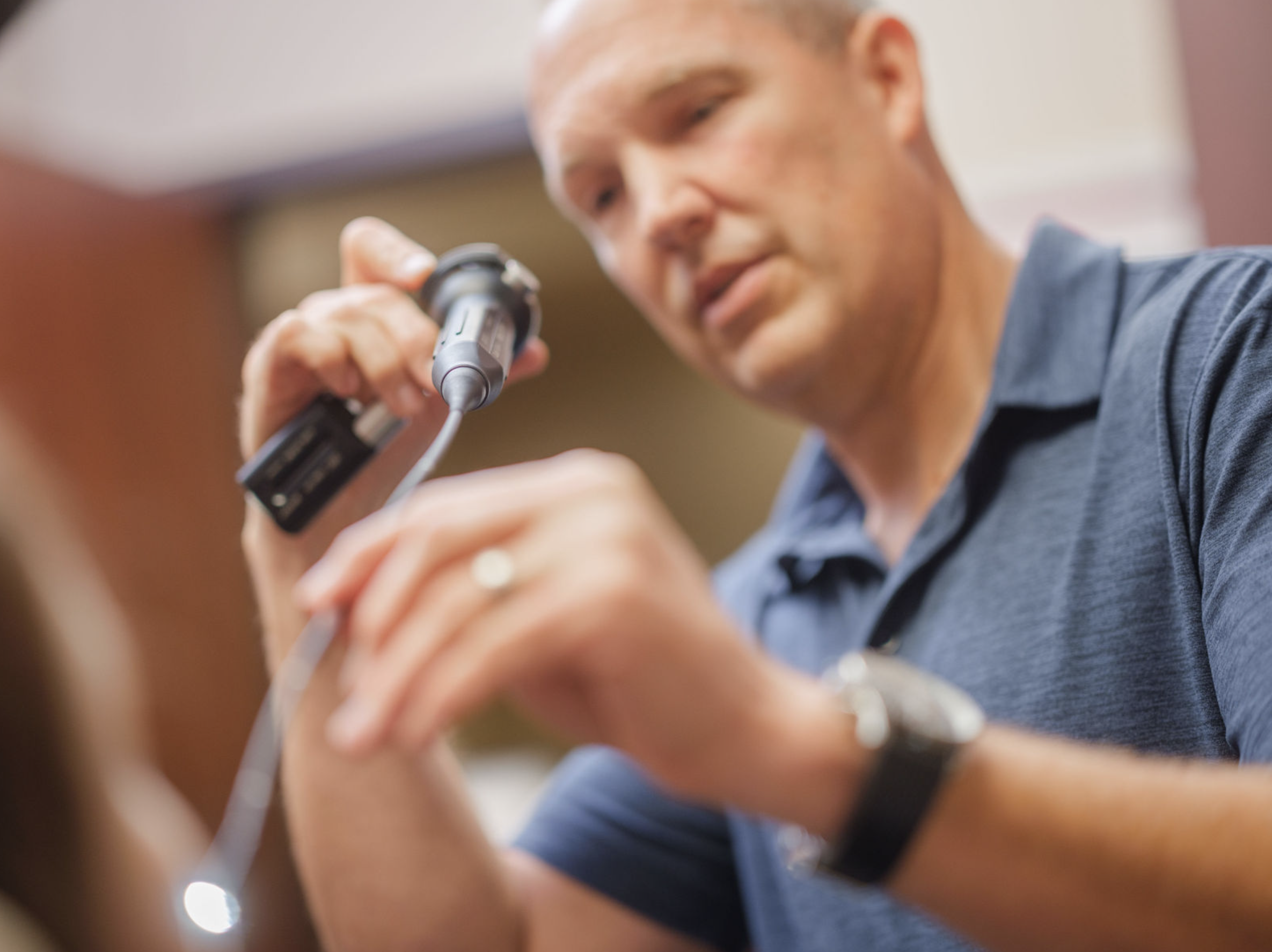 Doctor performing a medical examination using a diagnostic scope, showcasing professional, attentive patient care in a clinical setting.