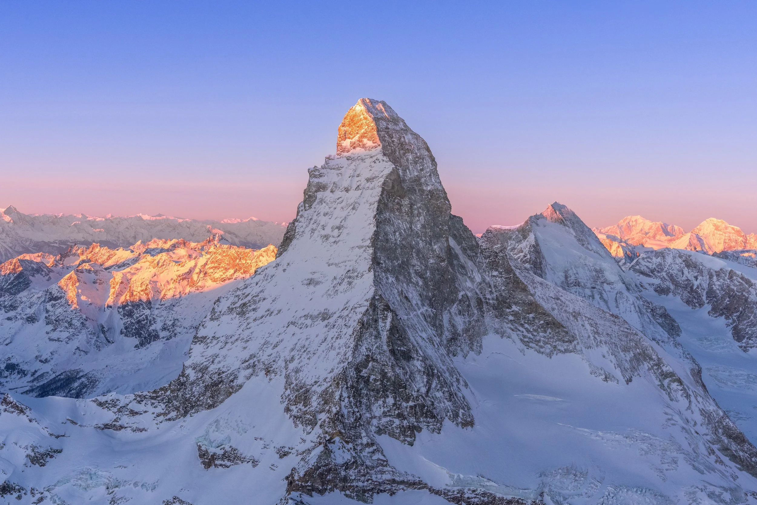 Berggipfel im Schnee bei Sonnenaufgang mit pinkfarbenem Himmel