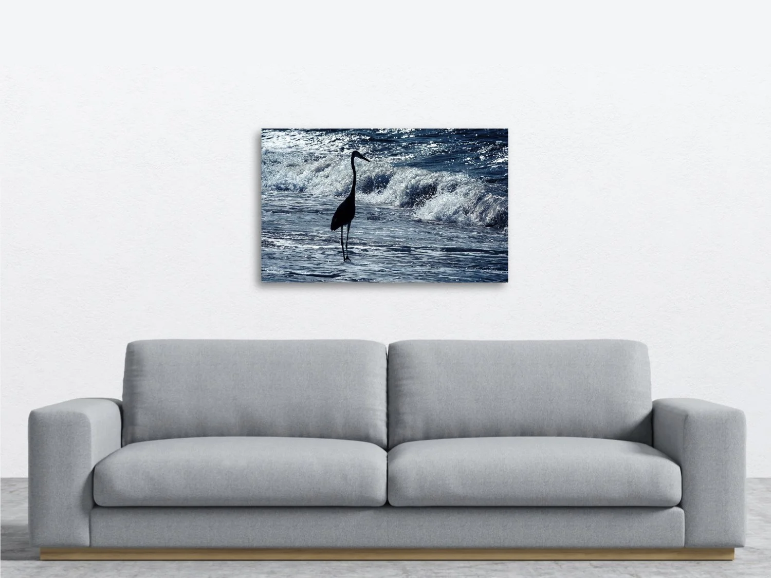 A photo of a blue heron standing quietly among blue waves sitting above a sofa