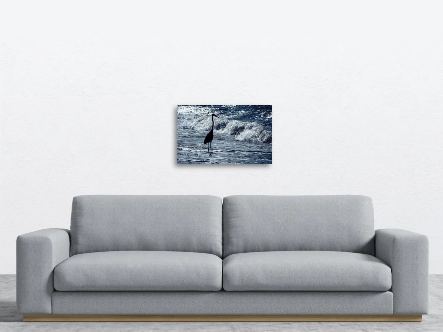 A photo of a blue heron standing quietly among blue waves sitting above a sofa