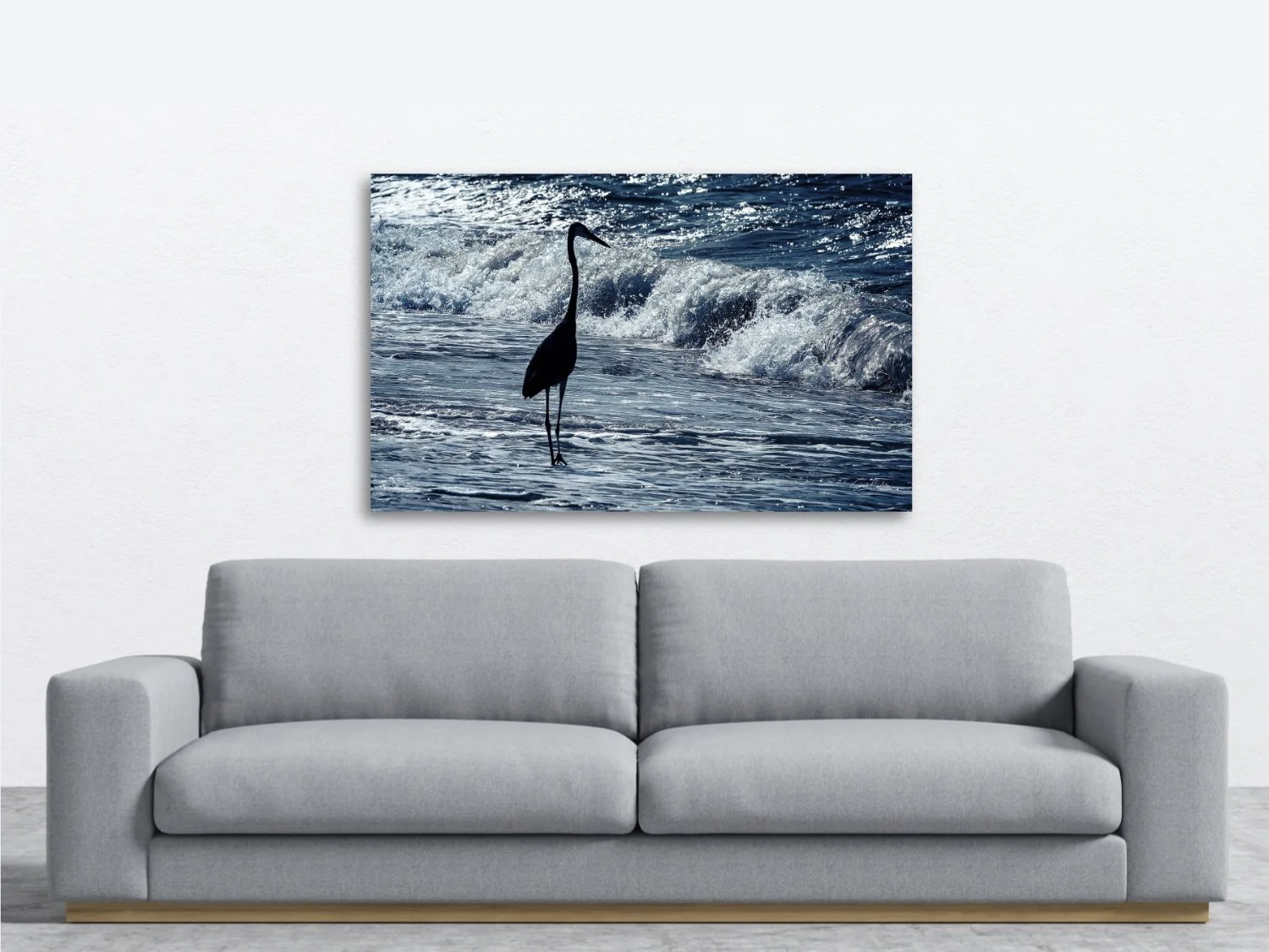 A photo of a blue heron standing quietly among blue waves sitting above a sofa.