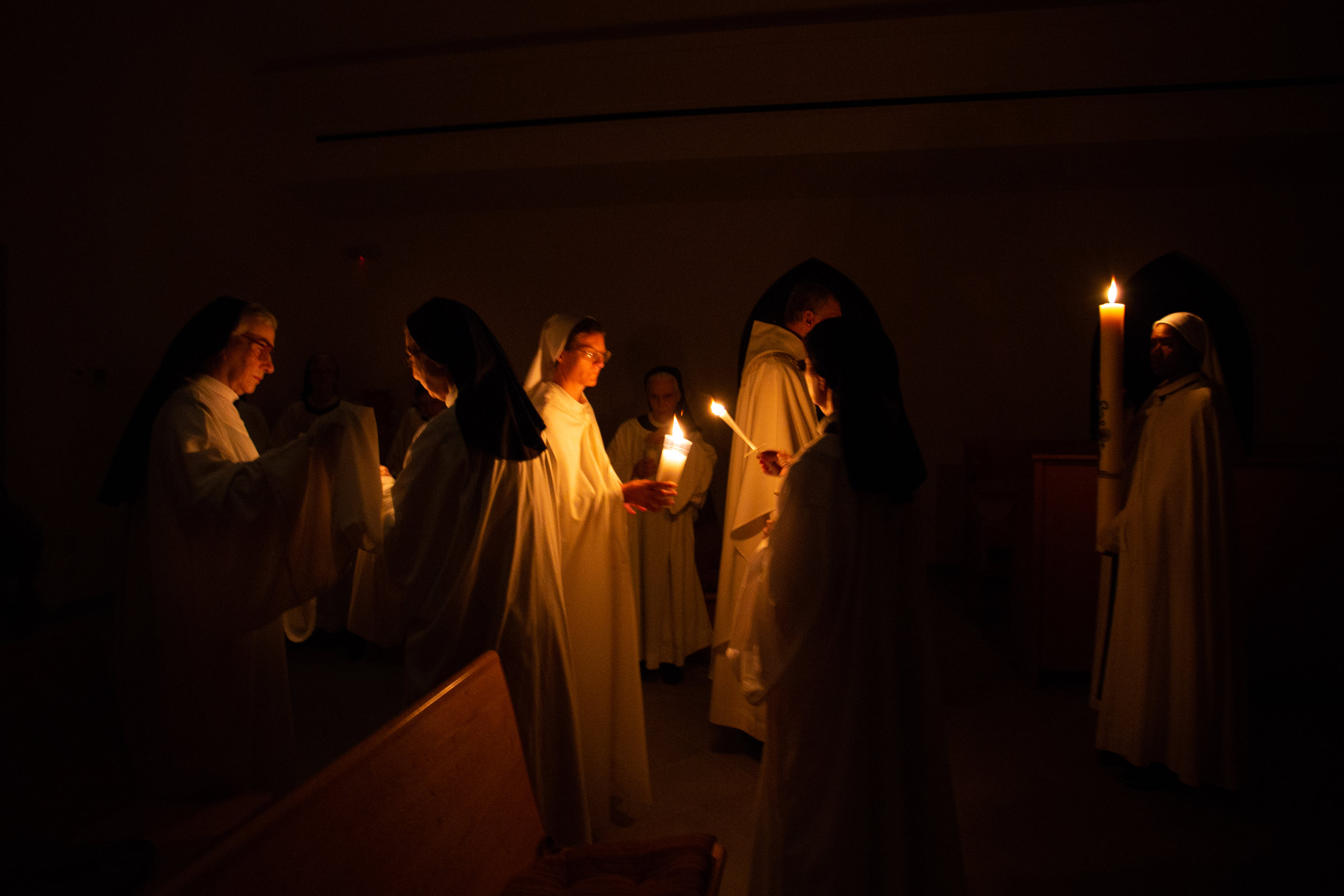  The sisters and guests stand in silence as they light candles Saturday evening April 20, 2019 in Crozet, Virginia. This ends their procession into the church for Easter mass. 