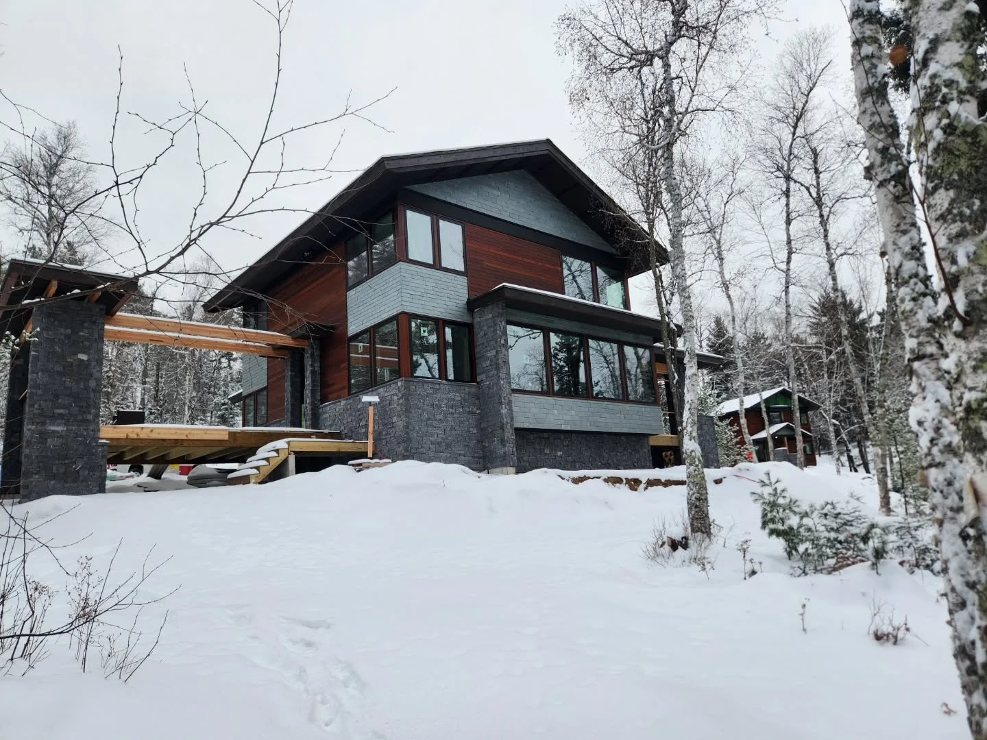 A mix of slate, drystack stone and ipe hardwood clad the siding to withstand brutal cold winters in Ely on Burntside Lake. Triple pane windows and insulated zip sheathing keep in the warmth. 

Architect: Mark Kawell
Designer: @cocoperrydesign 
Builde