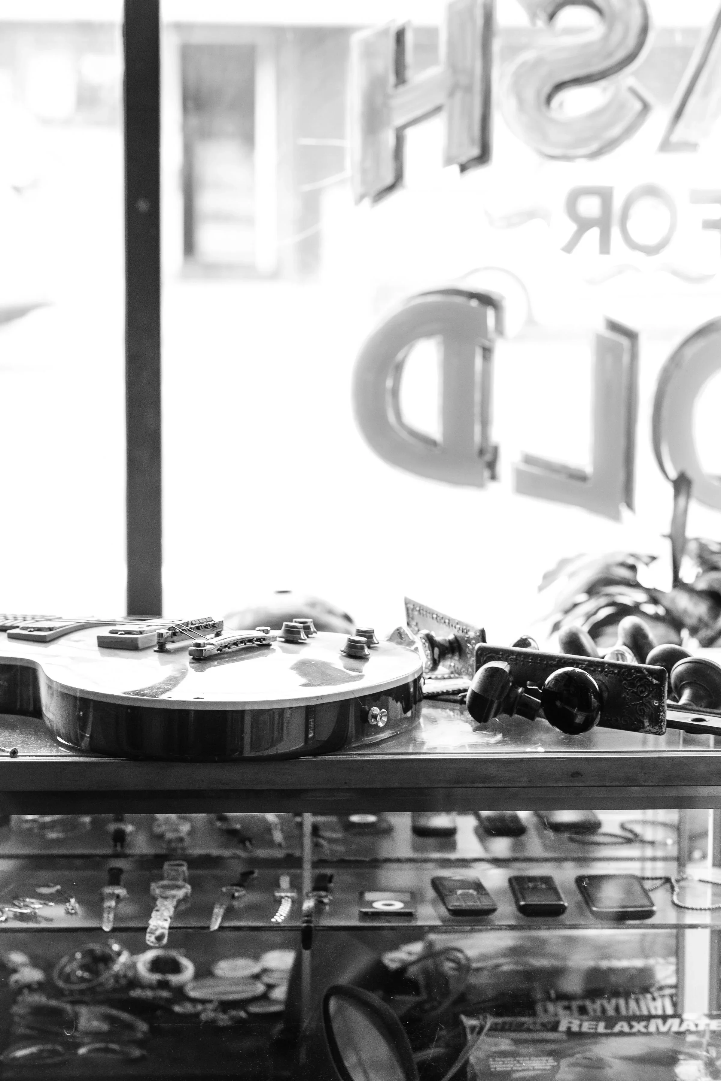 Black and white photo of a guitar and jewelry display in a store window.